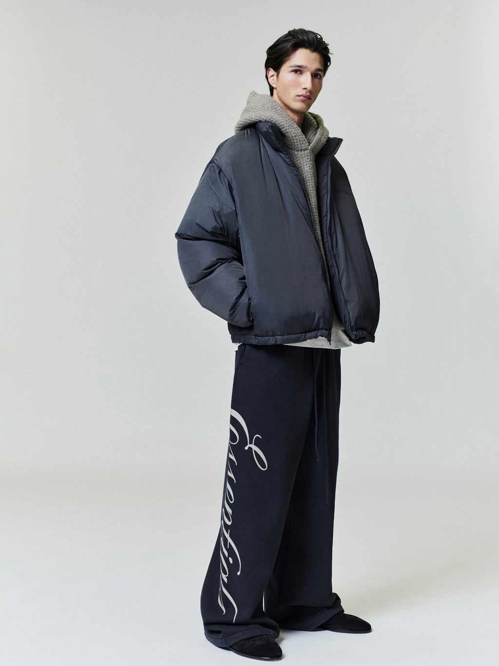 Full side view of model wearing oversized dark ripstop nylon puffer jacket with high collar, file 0001_HO25_F_L81_P41_4406.jpg