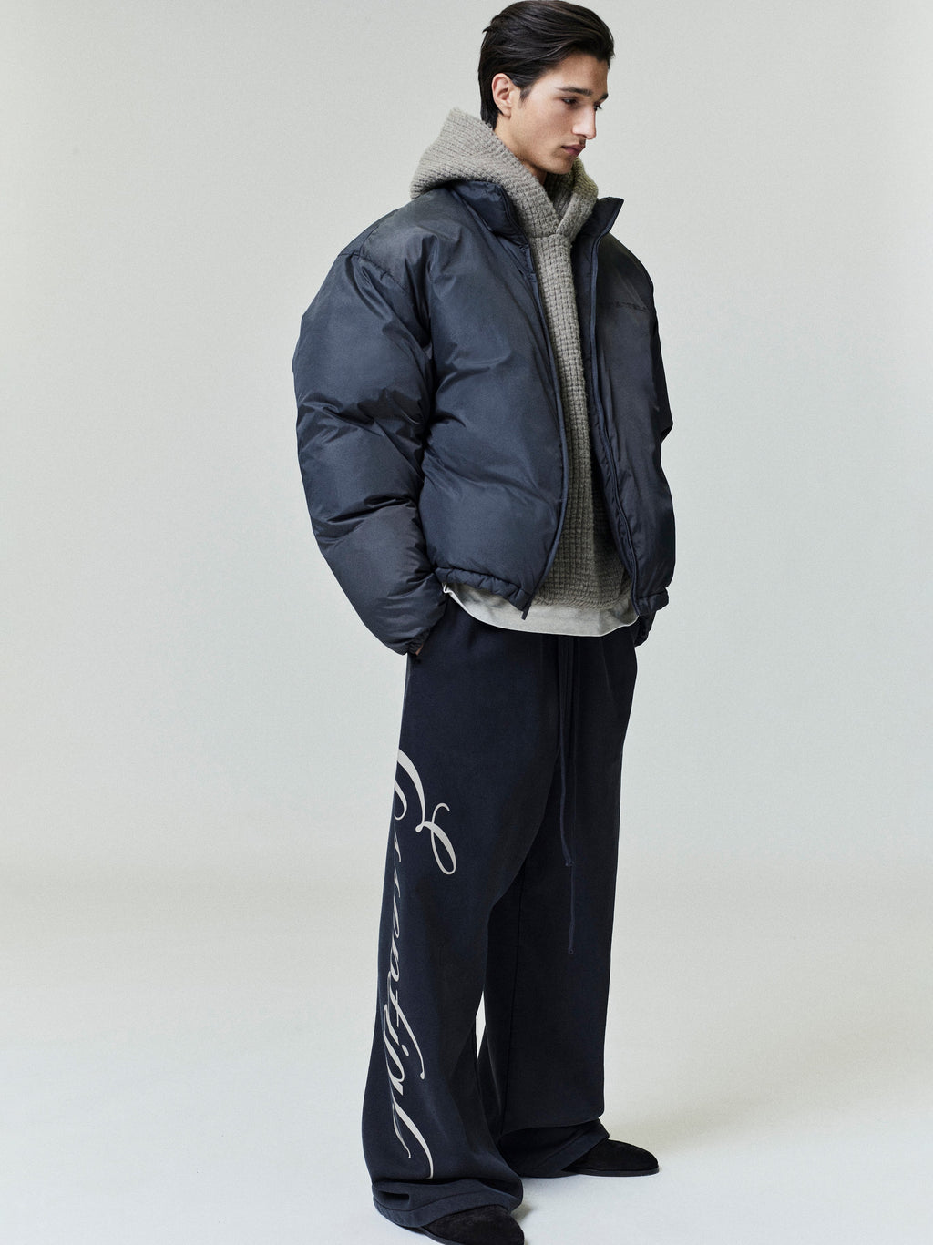 Three-quarter side view of model wearing dark ripstop nylon puffer jacket with high collar, file 0002_HO25_F_L81_P41_4379.jpg