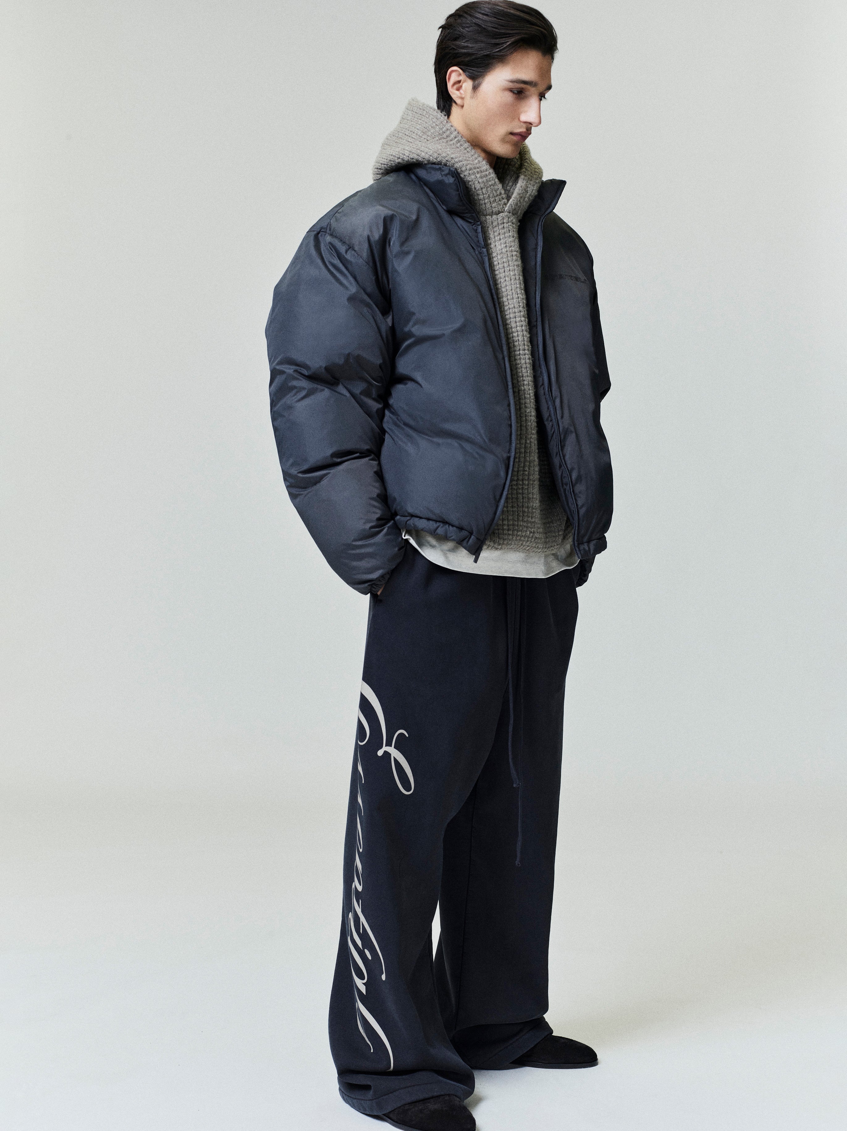 Three-quarter side view of model wearing dark ripstop nylon puffer jacket with high collar, file 0002_HO25_F_L81_P41_4379.jpg