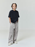 Full body view of child wearing black Kids Embroidered Essential Tee with relaxed fit, hands in pockets, gallery position 0