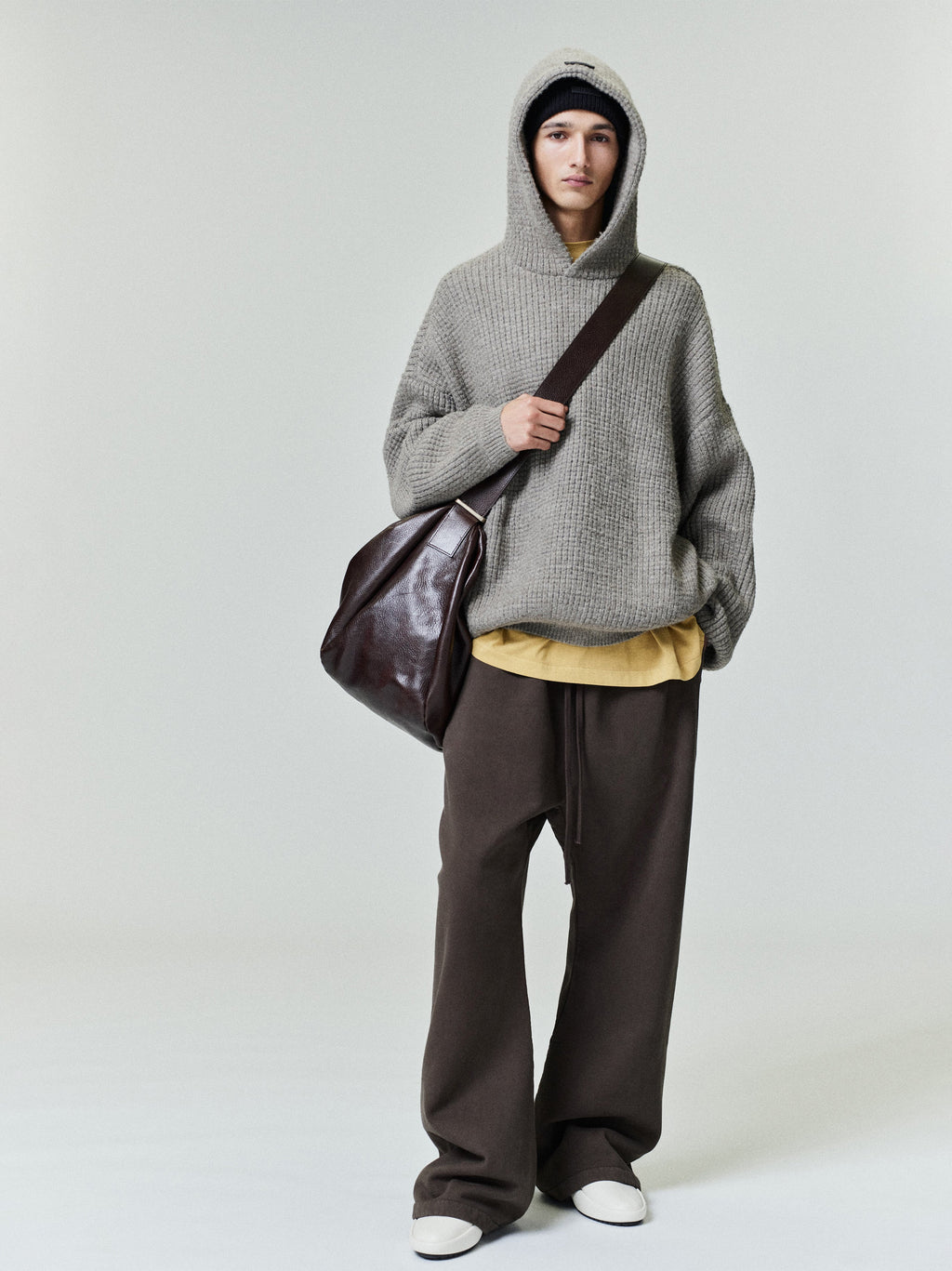 Model wearing dark brown Heavy Fleece Flare Sweatpant paired with oversized gray knit hoodie and dark leather shoulder bag, gallery 0