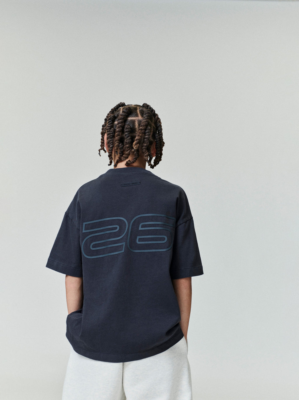 Child shown from back wearing navy Kids Classic Short Sleeve Tee with large subtle "26" print, gallery position 0, file 0007_HO25_K_L75_4009.jpg