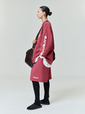 Side profile of model wearing oversize dusty rose 90s Long Sleeve Tee with white sleeve text and coordinating skirt, gallery 0.
