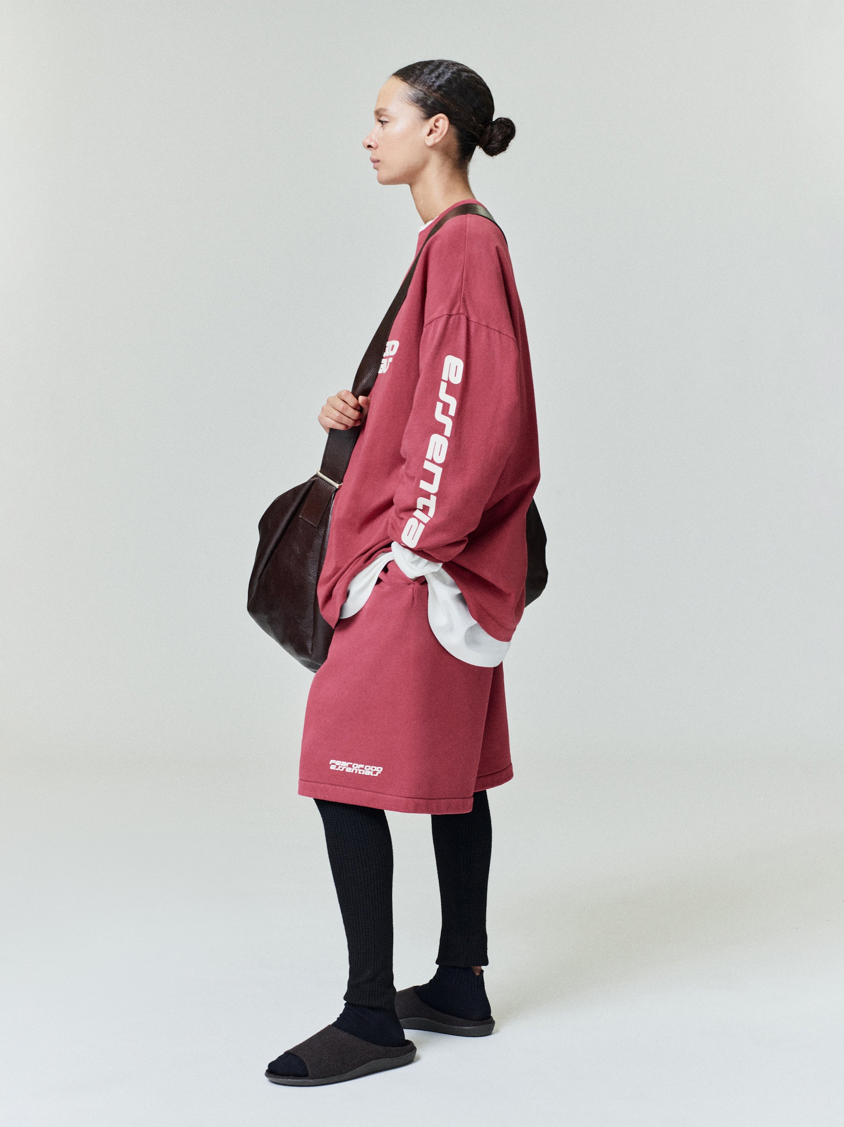 Side profile of model wearing oversize dusty rose 90s Long Sleeve Tee with white sleeve text and coordinating skirt, gallery 0.