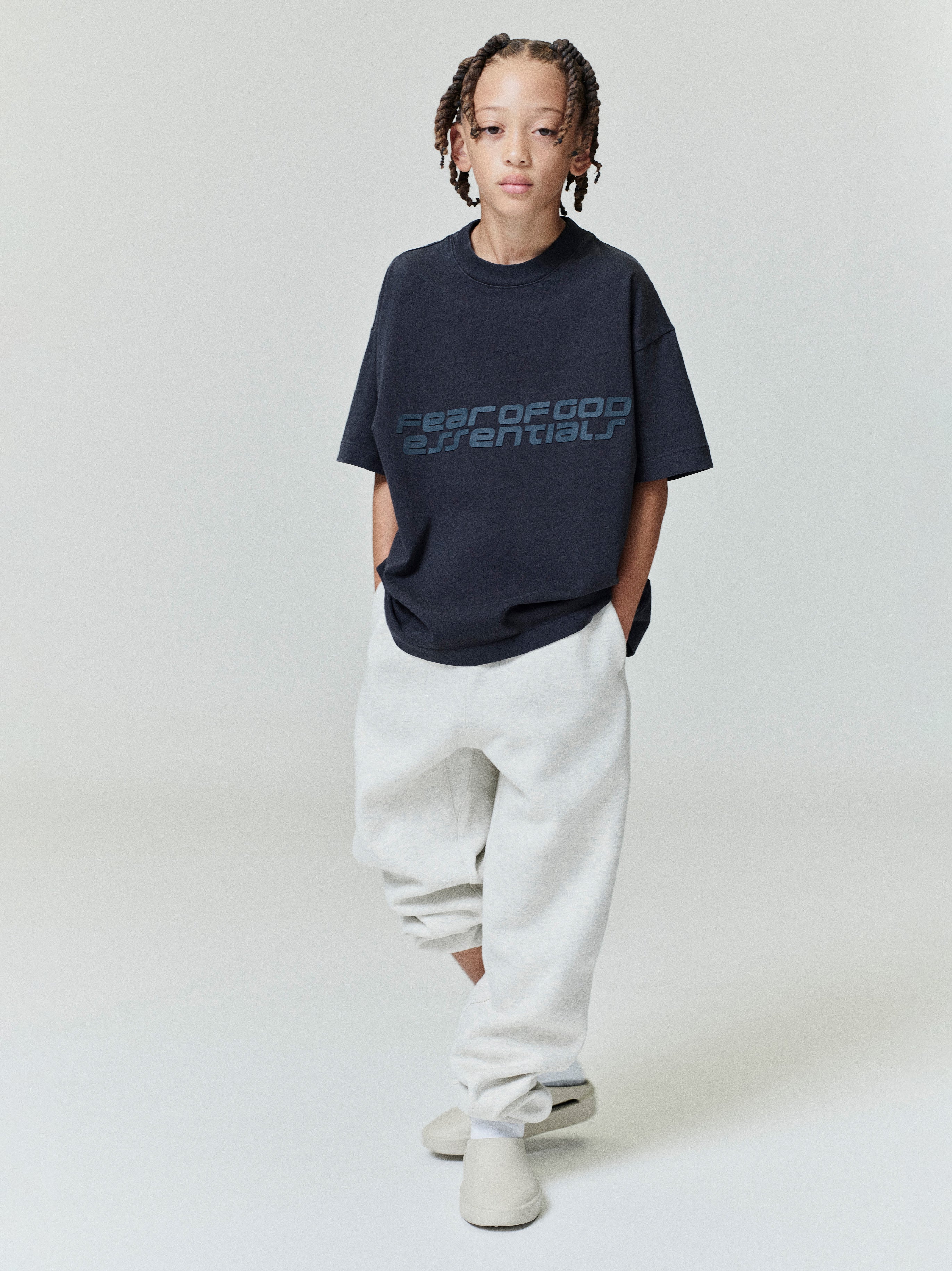 Child wearing navy Kids Classic Short Sleeve Tee with subtle logo print, standing front view, gallery position 0, file 0008_HO25_K_L75_4004.jpg