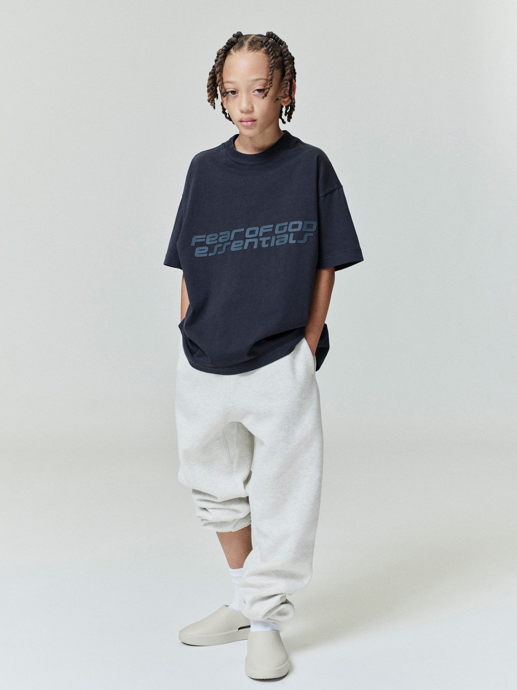 Child wearing navy Kids Classic Short Sleeve Tee with subtle logo print, standing front view, gallery position 0, file 0009_HO25_K_L75_4000.jpg