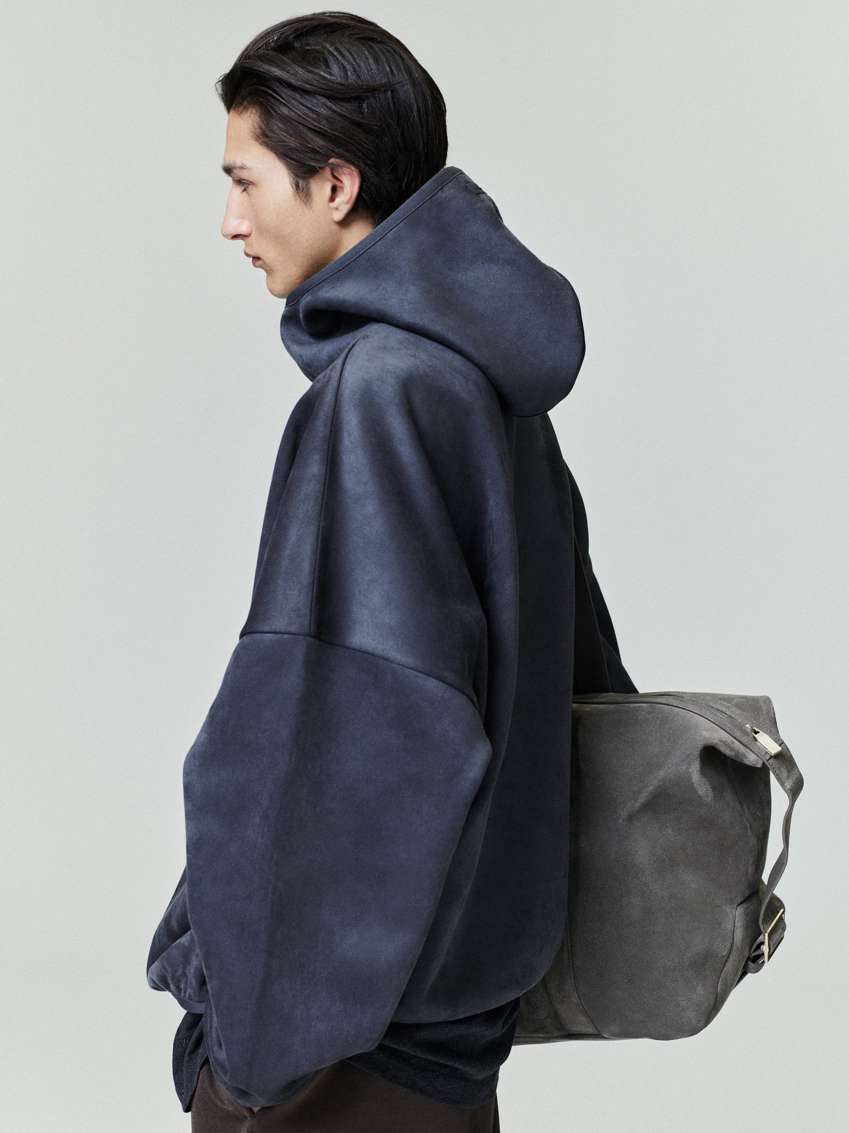 Profile of model wearing dark navy suede fleece modern hoodie with oversized fit and gray suede backpack 0011_HO25_F_L26_3202.jpg