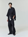 Full-length shot of model wearing black denim work pant and matching oversized half-sleeve shirt on neutral background