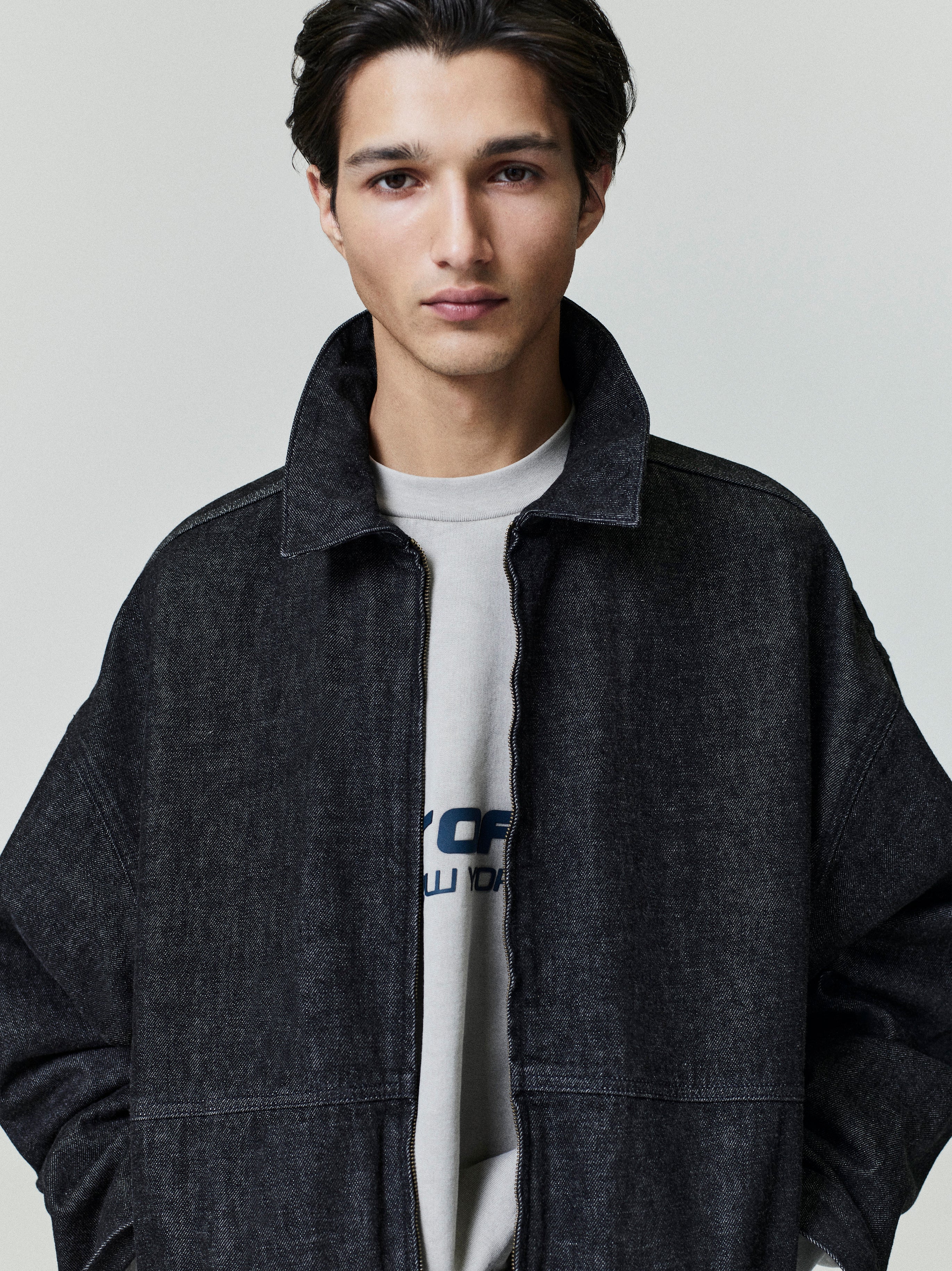 Close-up front view of model wearing dark washed denim work jacket with open collar, file 0018_HO25_F_L45_1464.jpg