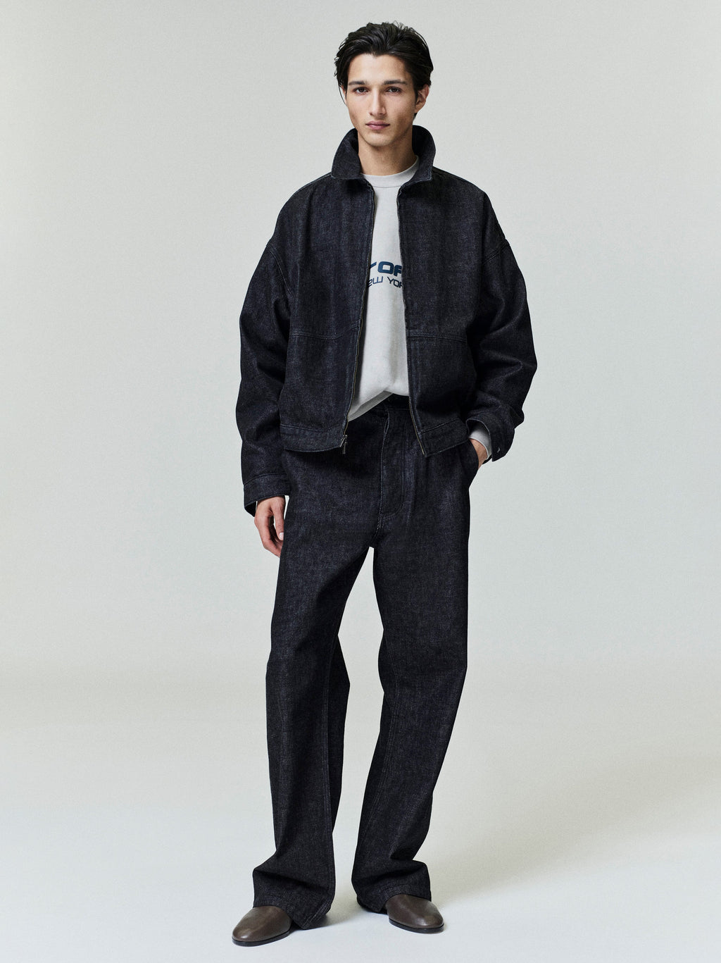 Front view of model wearing dark denim work jacket and matching loose-fit jeans, gallery position 0, file 0020_HO25_F_L45_1362.jpg