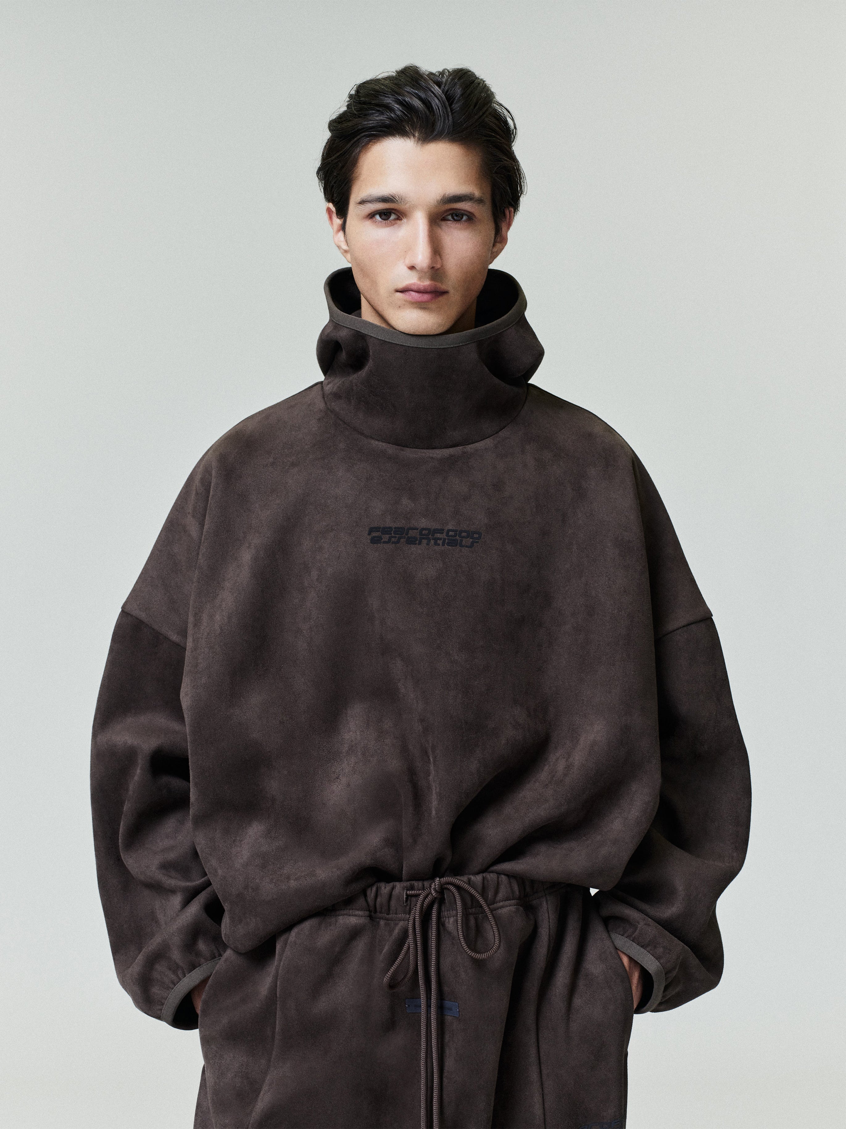 Portrait of model wearing dark brown suede fleece modern hoodie with high funnel neck, file 0022_HO25_F_L17_2137_OnModelImage.jpg