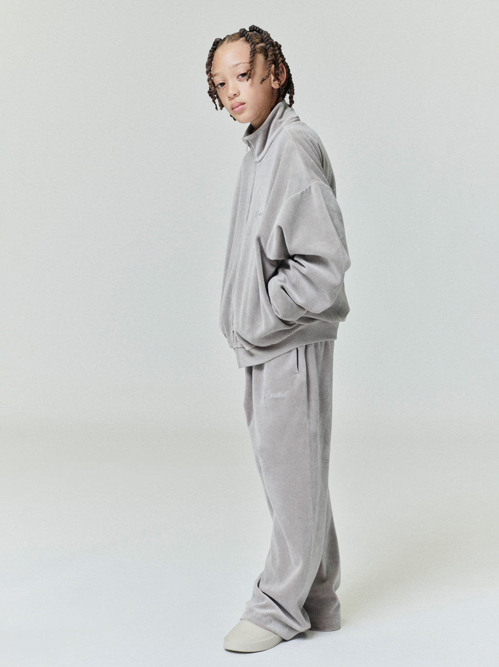 Side profile of child modeling light gray velour flare sweatpants with matching oversized zip-up jacket on plain background