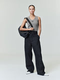 Woman wearing a fitted gray waffle tank with wide-leg black pants and carrying a black shoulder bag standing with one hand in pocket