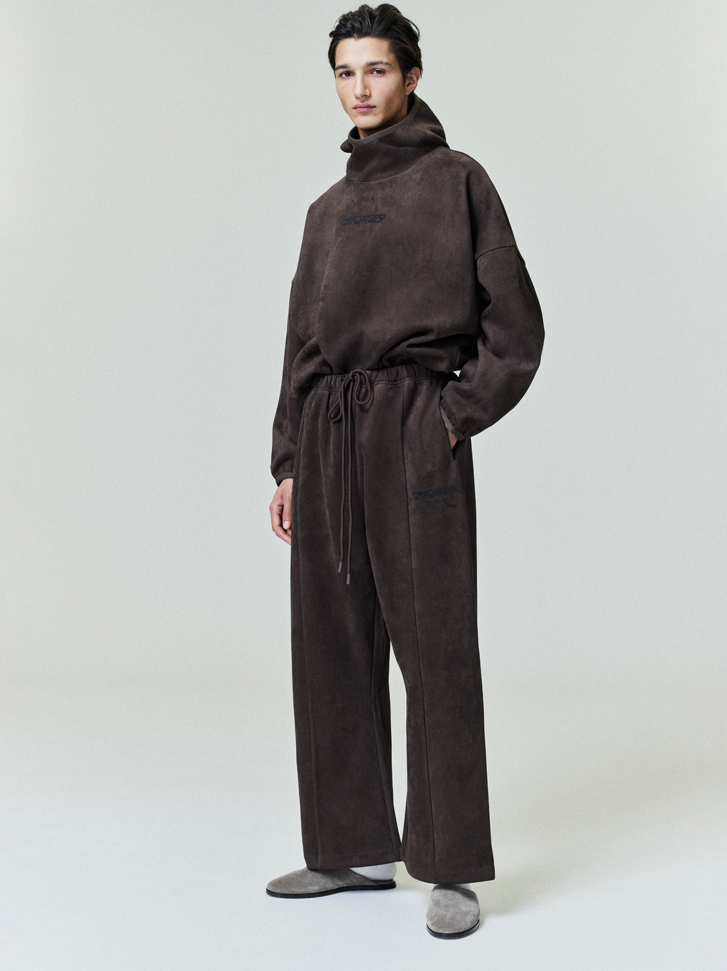Model wearing dark brown Suede Fleece Flare Pant with drawstring waist and relaxed fit, front view on neutral background
