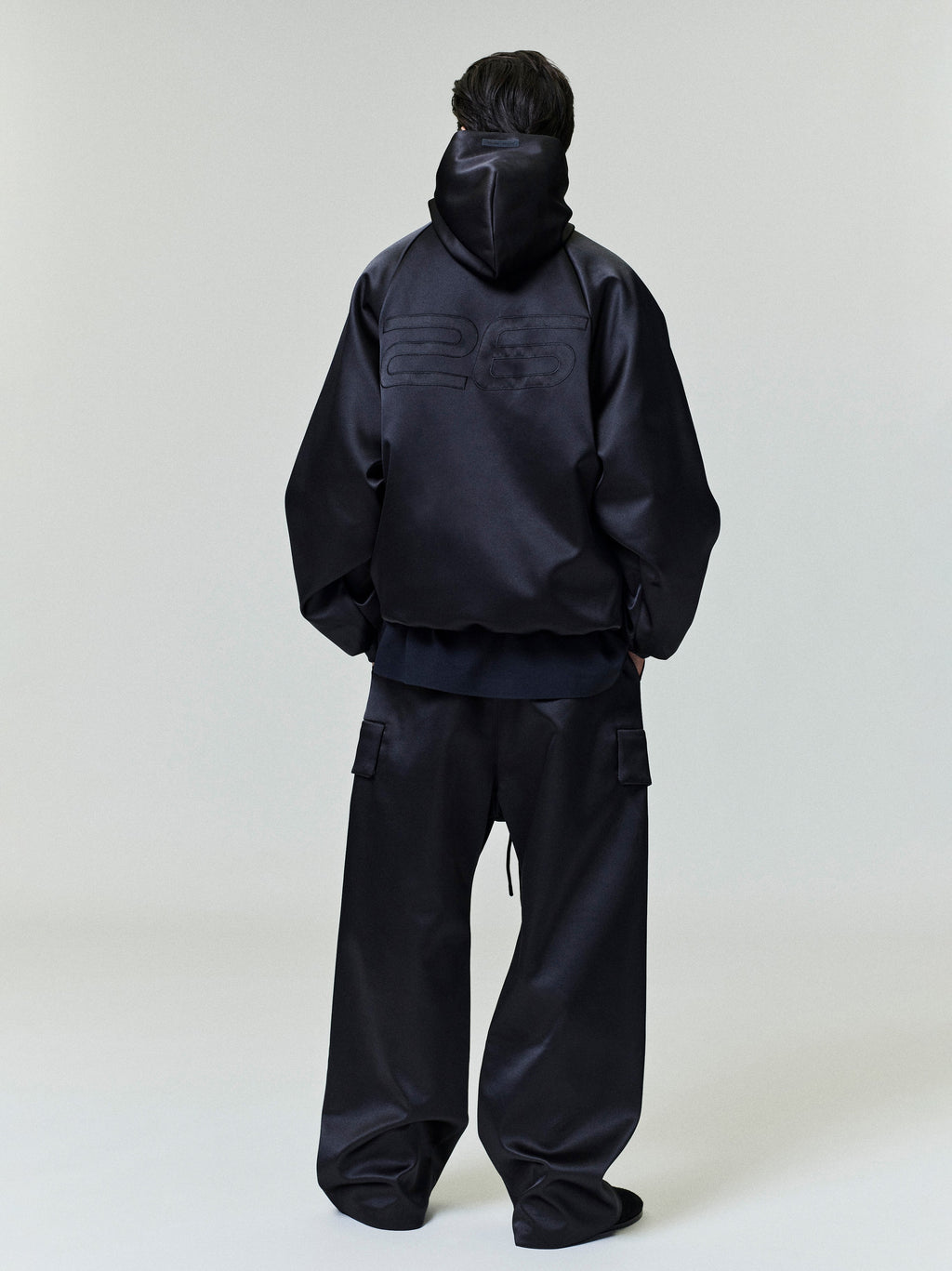 Model seen from behind wearing black Bonded Satin Field Pant with cargo pockets and matching black jacket, gallery 0 file 0025_HO25_F_L77_P40_4117.jpg