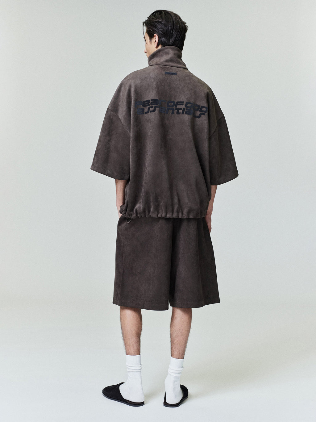 Male model shown from back wearing brown Suede Fleece Relaxed Short and matching half-zip top with graphic print on back