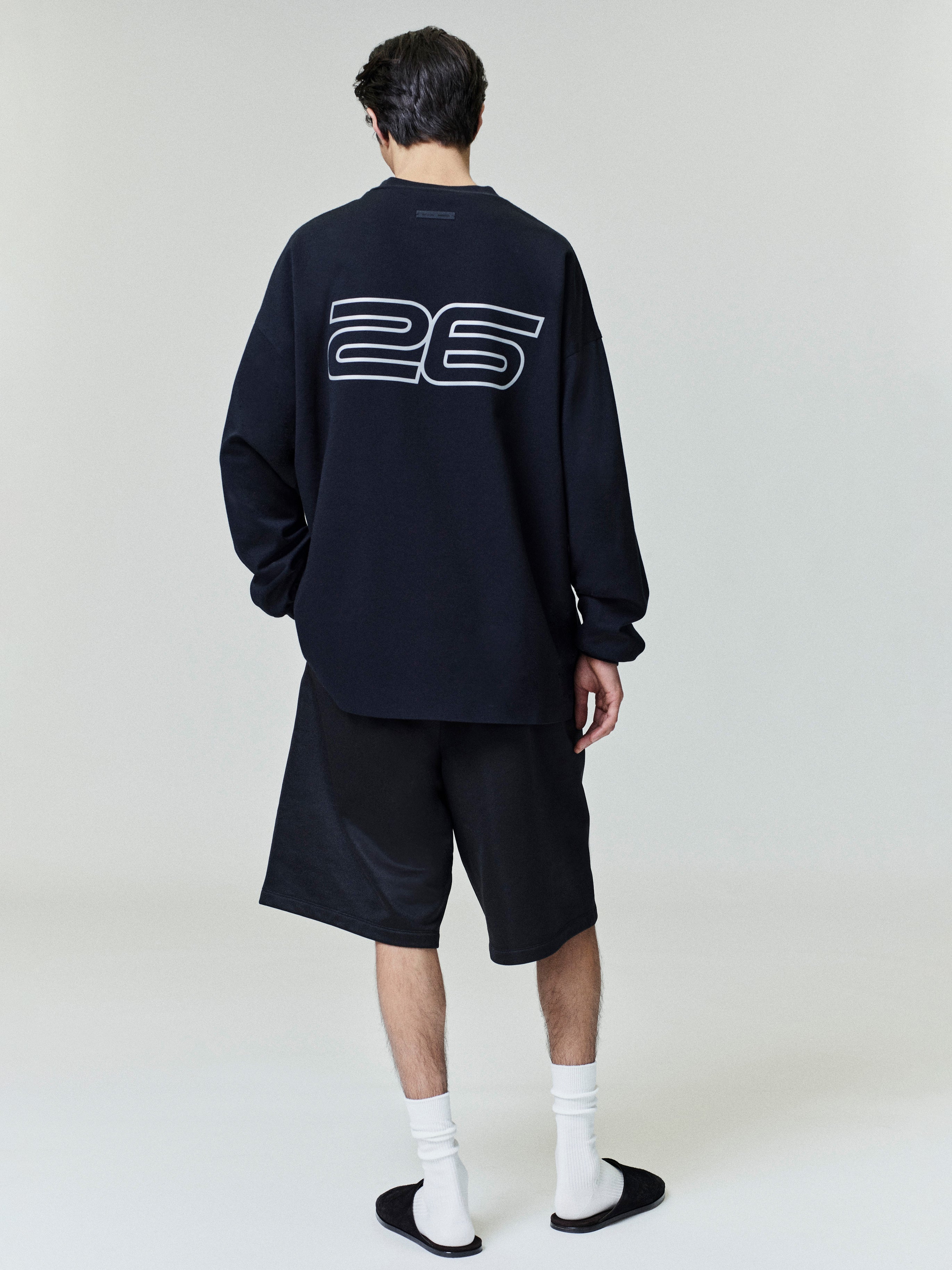 Male model seen from back wearing black Ponte 90s Long Sleeve Tee with large outlined "26" graphic, gallery 0027_HO25_F_L41_P01_0917copy.jpg