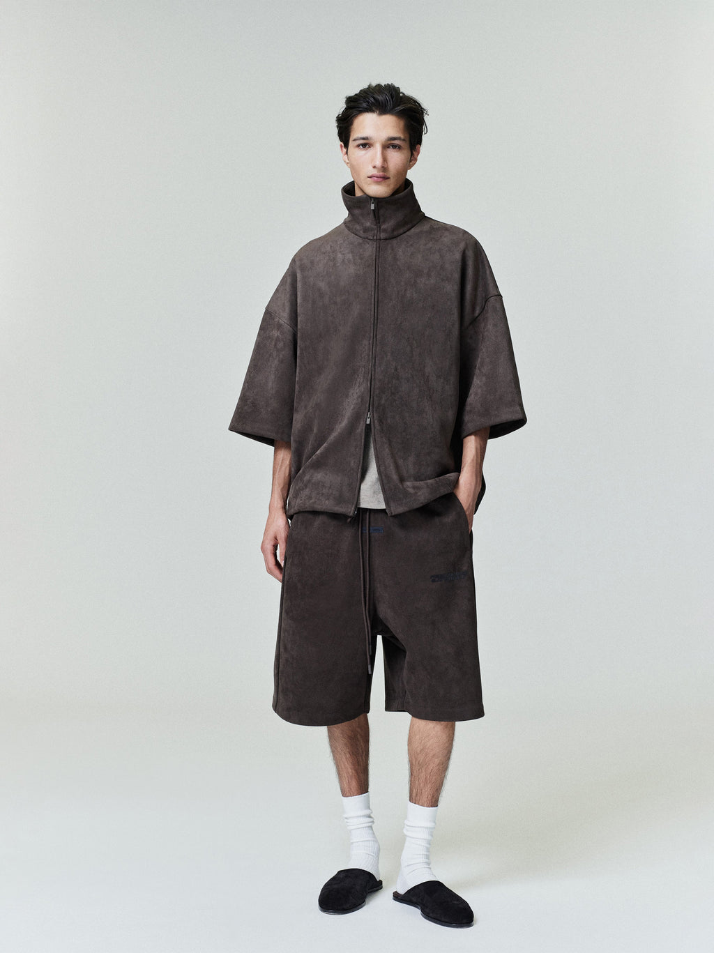 Model wearing brown Suede Fleece Relaxed Short with matching half-zip top in minimalist studio setting