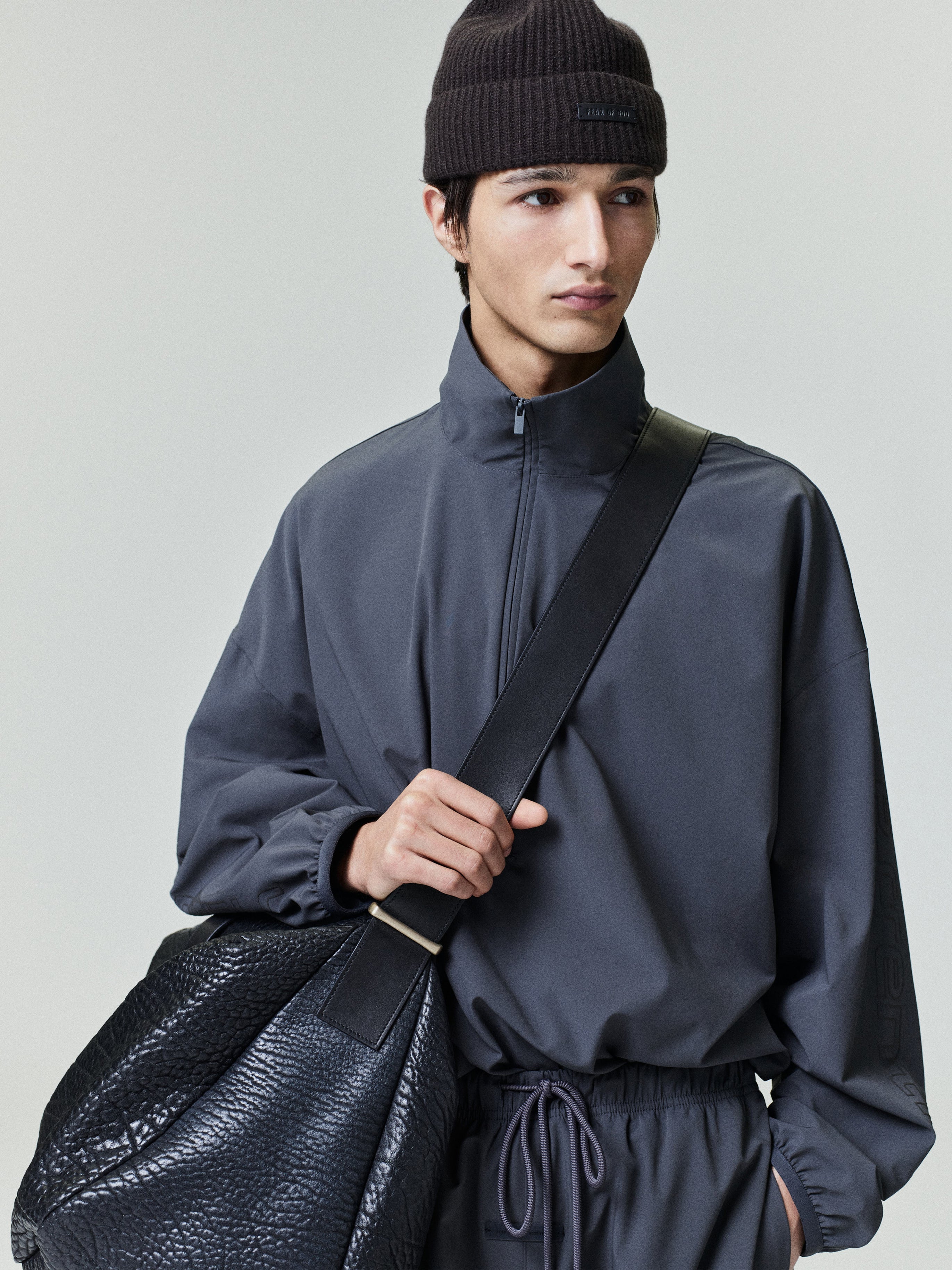 Model wearing dark charcoal Tech Nylon Half Zip Track Jacket with high collar and black crossbody bag, gallery 0