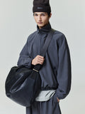 Model wearing charcoal Tech Nylon Half Zip Track Jacket and coordinating pants holding large black textured bag, gallery 0