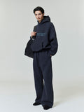Full-length shot of model wearing dark navy Heavy Fleece 90s Hoodie with matching wide-leg pants and carrying large black bag gallery 0
