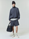 Model wearing dark iron grey Tech Nylon Classic Shorts paired with oversized pullover and black textured leather bag