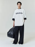 Model wearing off-white Ponte 90s Tee with black Fear of God Essentials logo, holding large textured black bag, gallery image 0