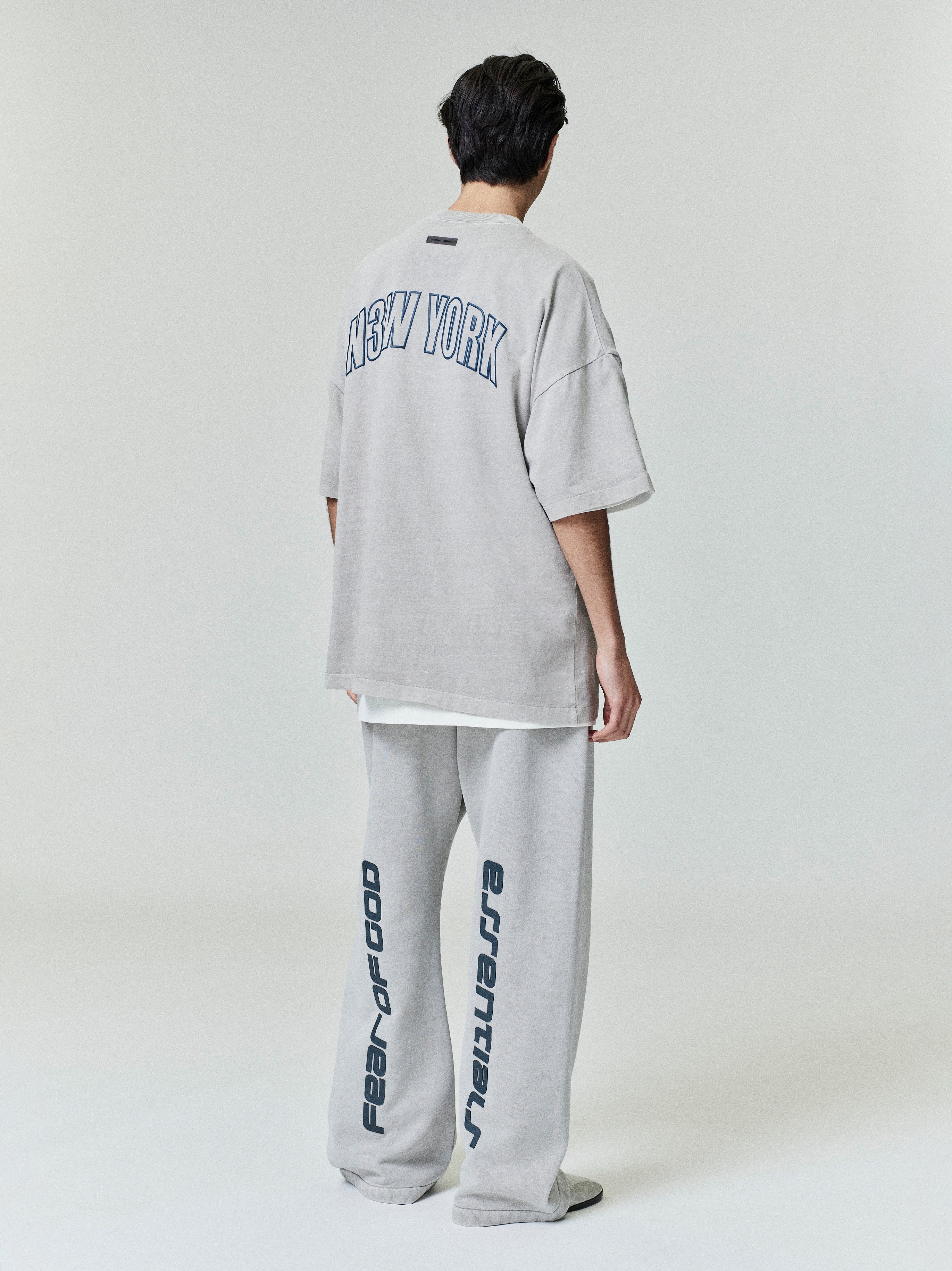 Rear view of model wearing oversized New York 90s Tee with navy arch print and matching wide sweatpants with vertical lettering