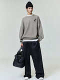 Model wearing black Satin Fleece Lounge Sweatpant with wide leg and subtle embossed logo, holding black leather bag, gallery 0