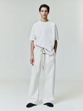 Male model wearing relaxed fit ivory Embroidered Essential Tee and matching wide-leg pants, full front studio view