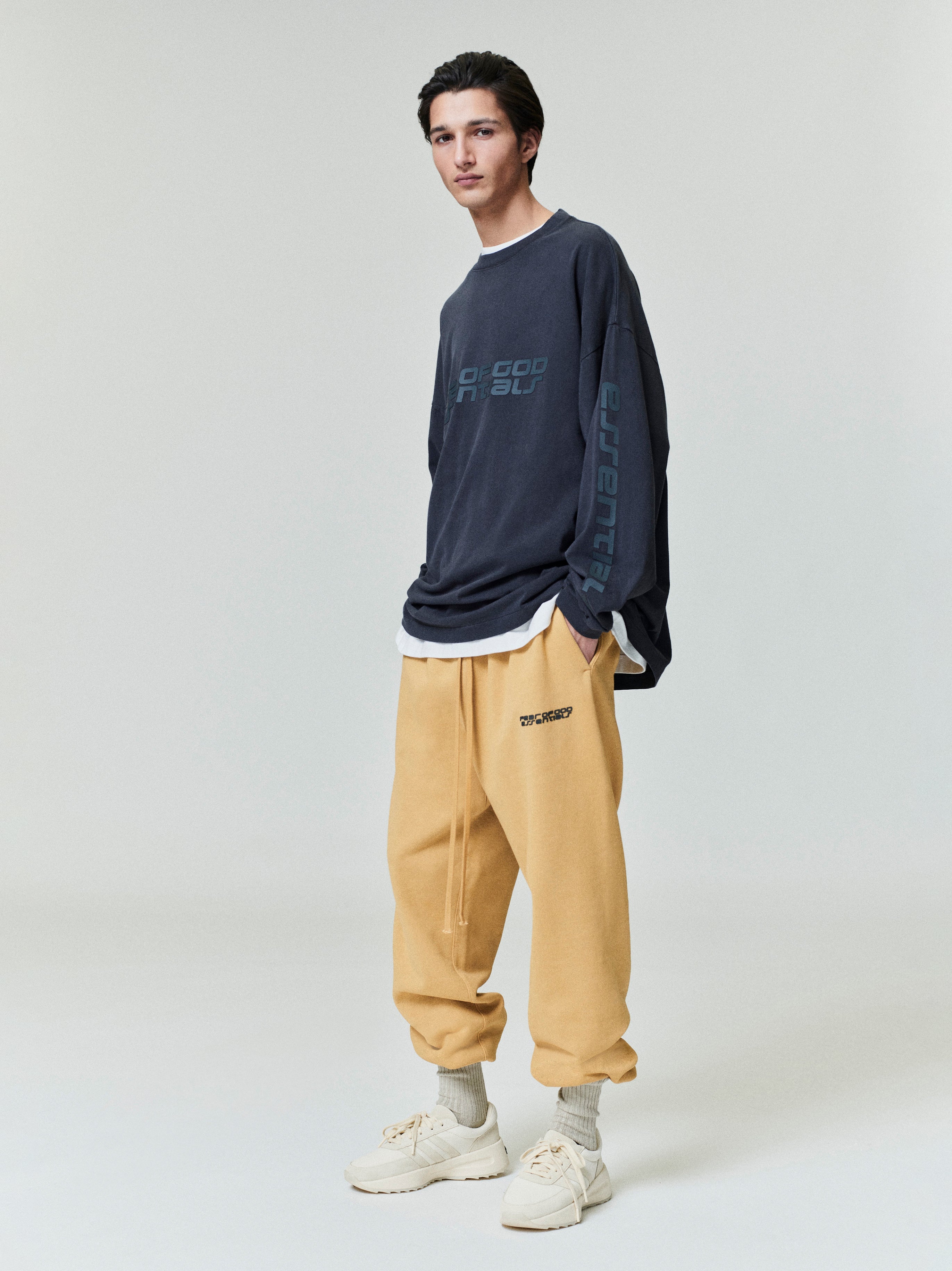 Model wearing navy 90s Long Sleeve Tee with subtle branding on chest and sleeve, styled with tan sweatpants, gallery 0.