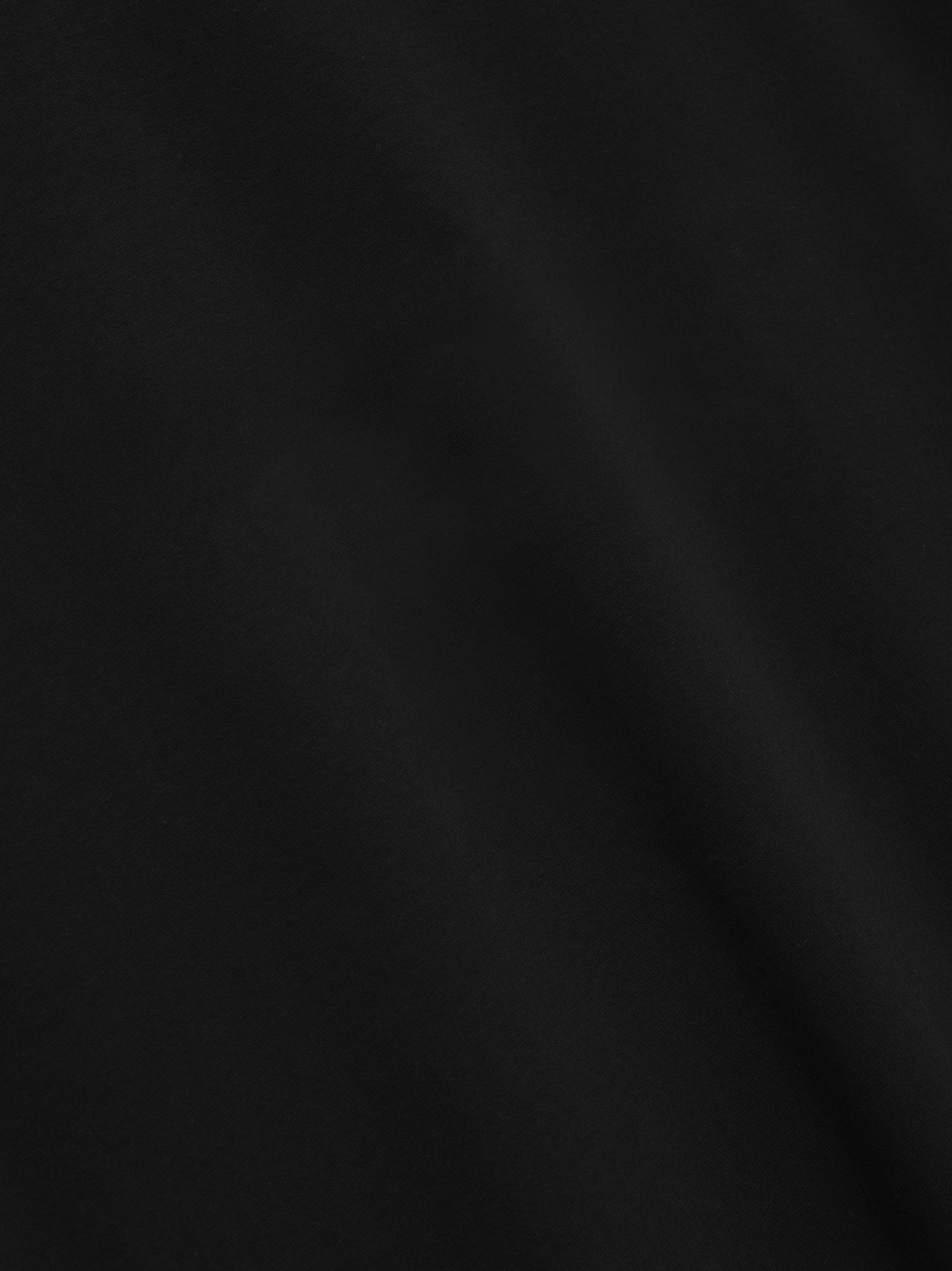 Close-up of smooth black fabric texture with subtle, soft folds and no visible patterns or logos