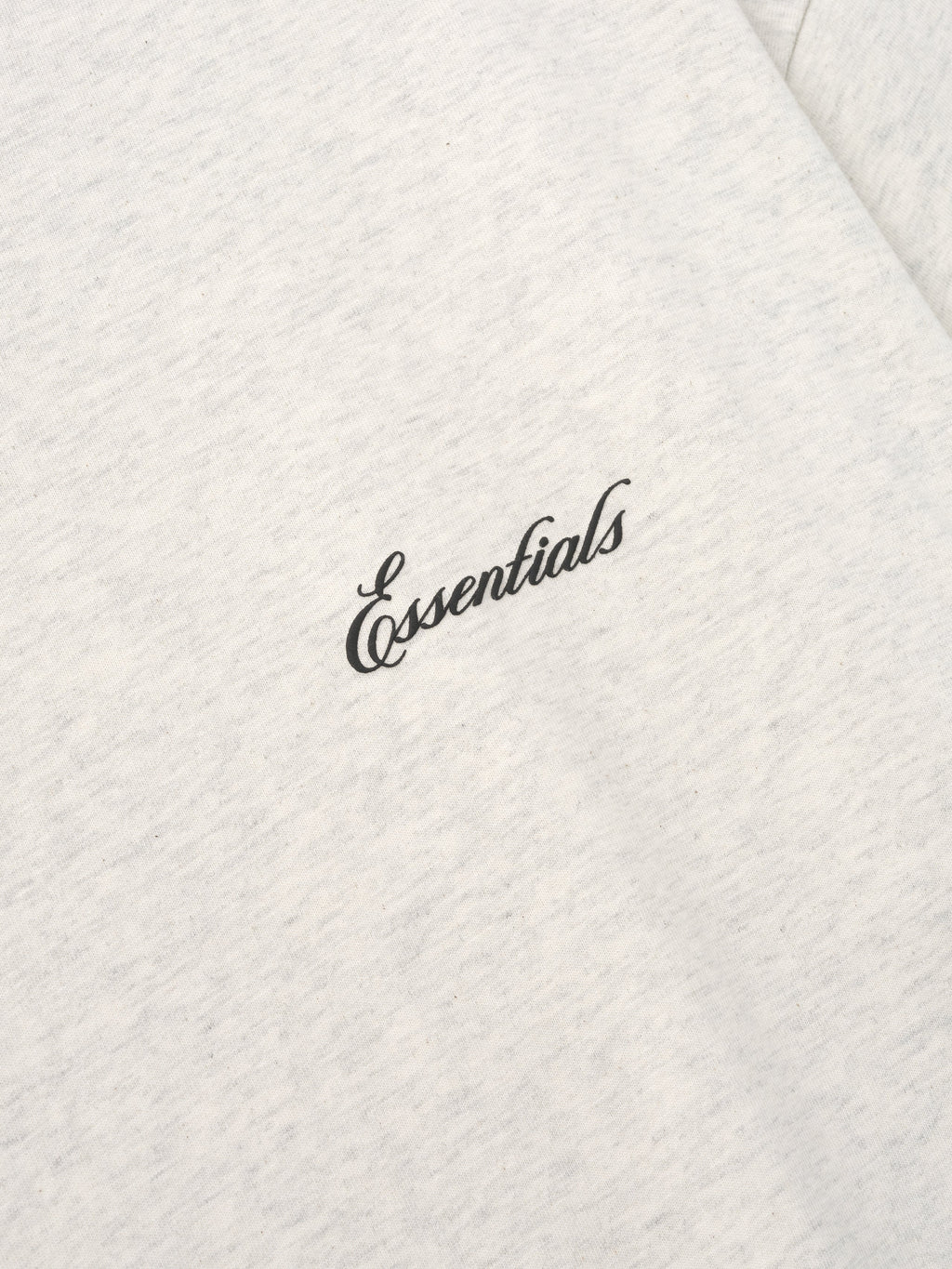 Close up of a white t-shirt with essentials script logo on a white background