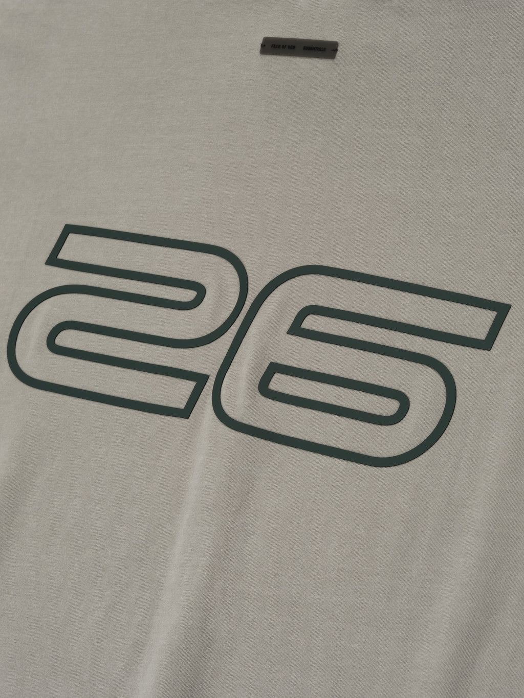 Close-up of smoke grey Fear of God Essentials 90s Tee showing large outlined 26 print on soft cotton fabric