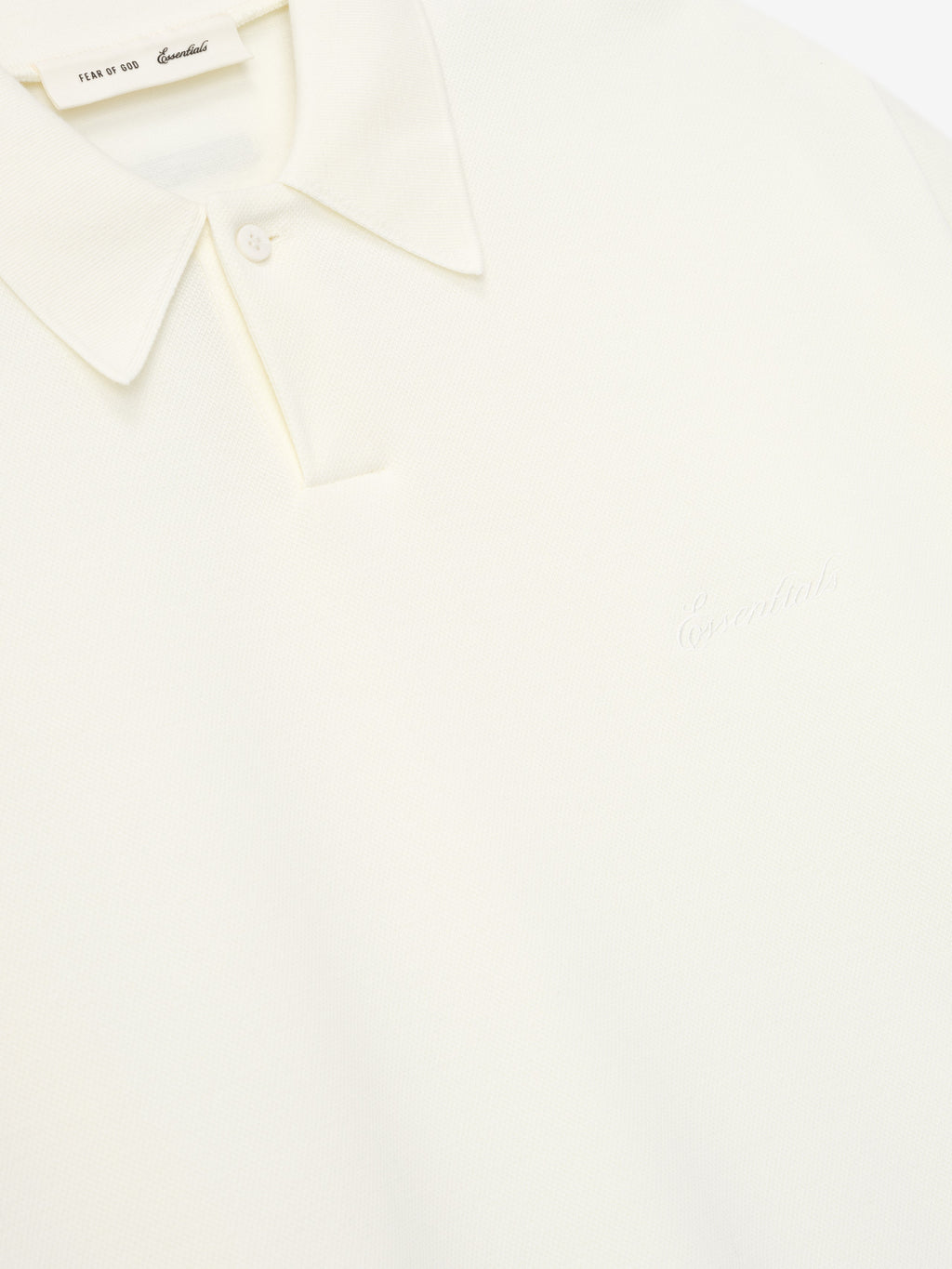 close-up of off-white medium-weight cotton poly pique polo with classic collar and subtle embossed branding on chest