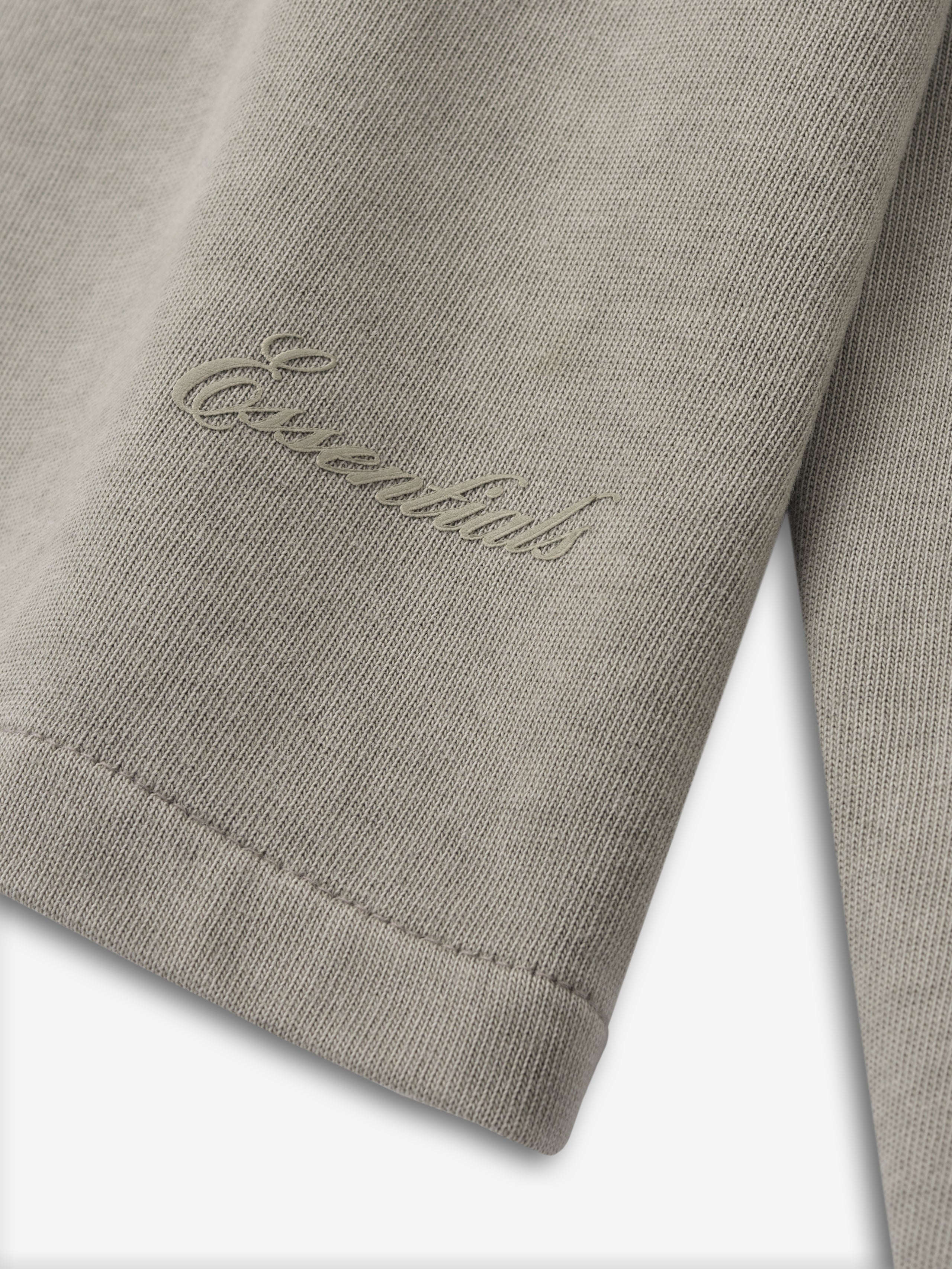 close-up of beige heavyweight cotton jersey long sleeve tee cuff with tonal Essentials embossed logo detail