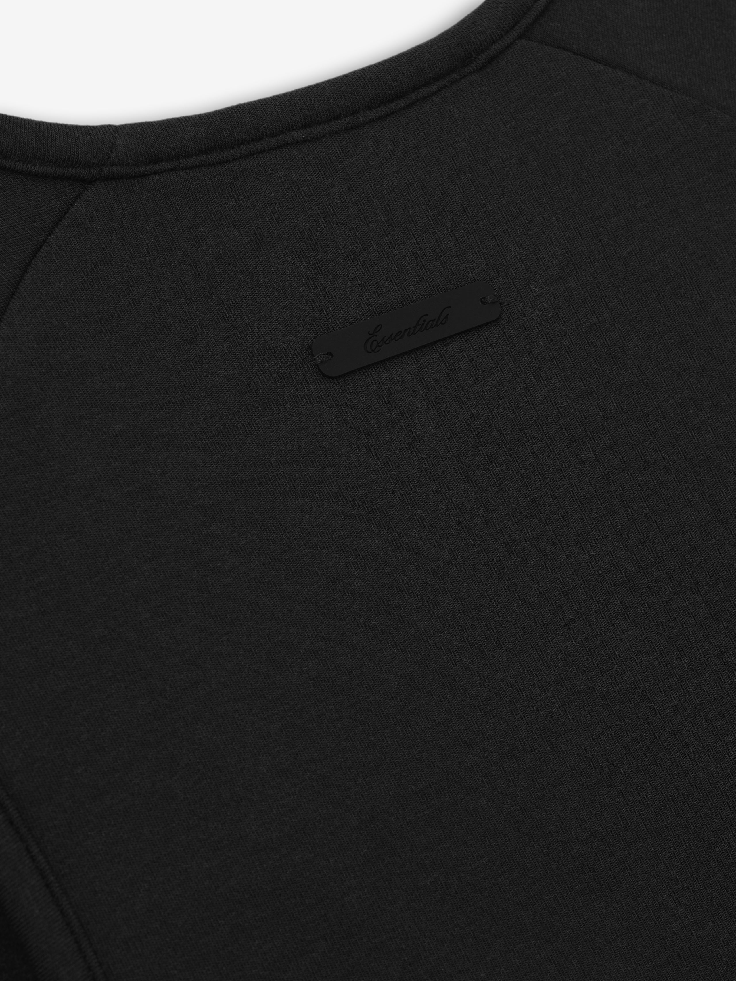 close-up of black brushed jersey fabric with stitched Essentials signature label on back collar of women's tank