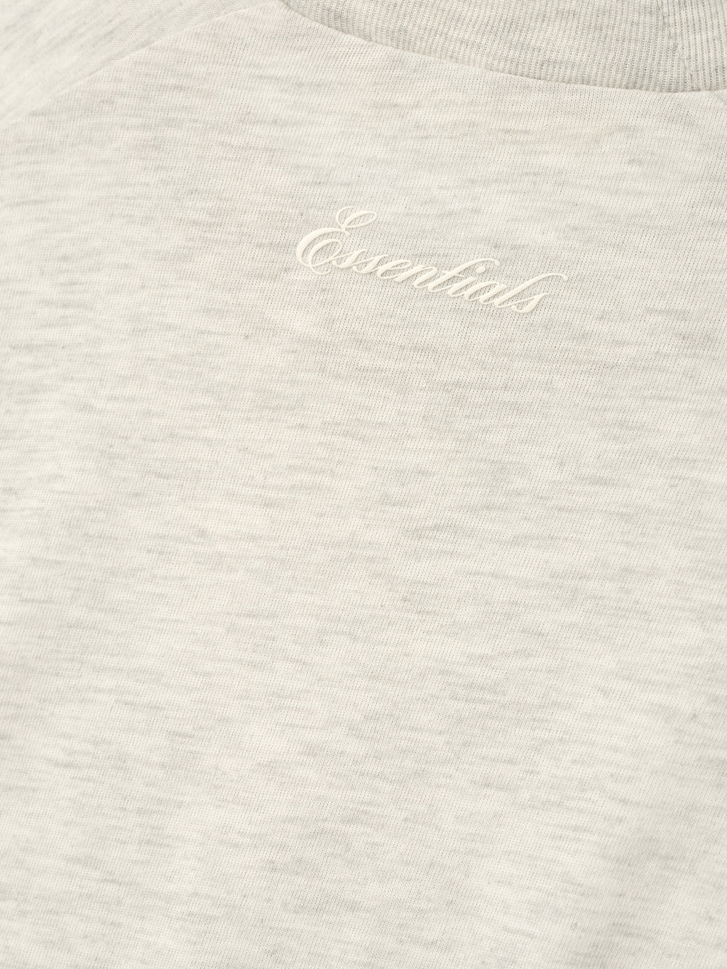 close-up of soft heather natural cotton blend jersey with subtle puff-printed Essentials script logo on women's long sleeve tee