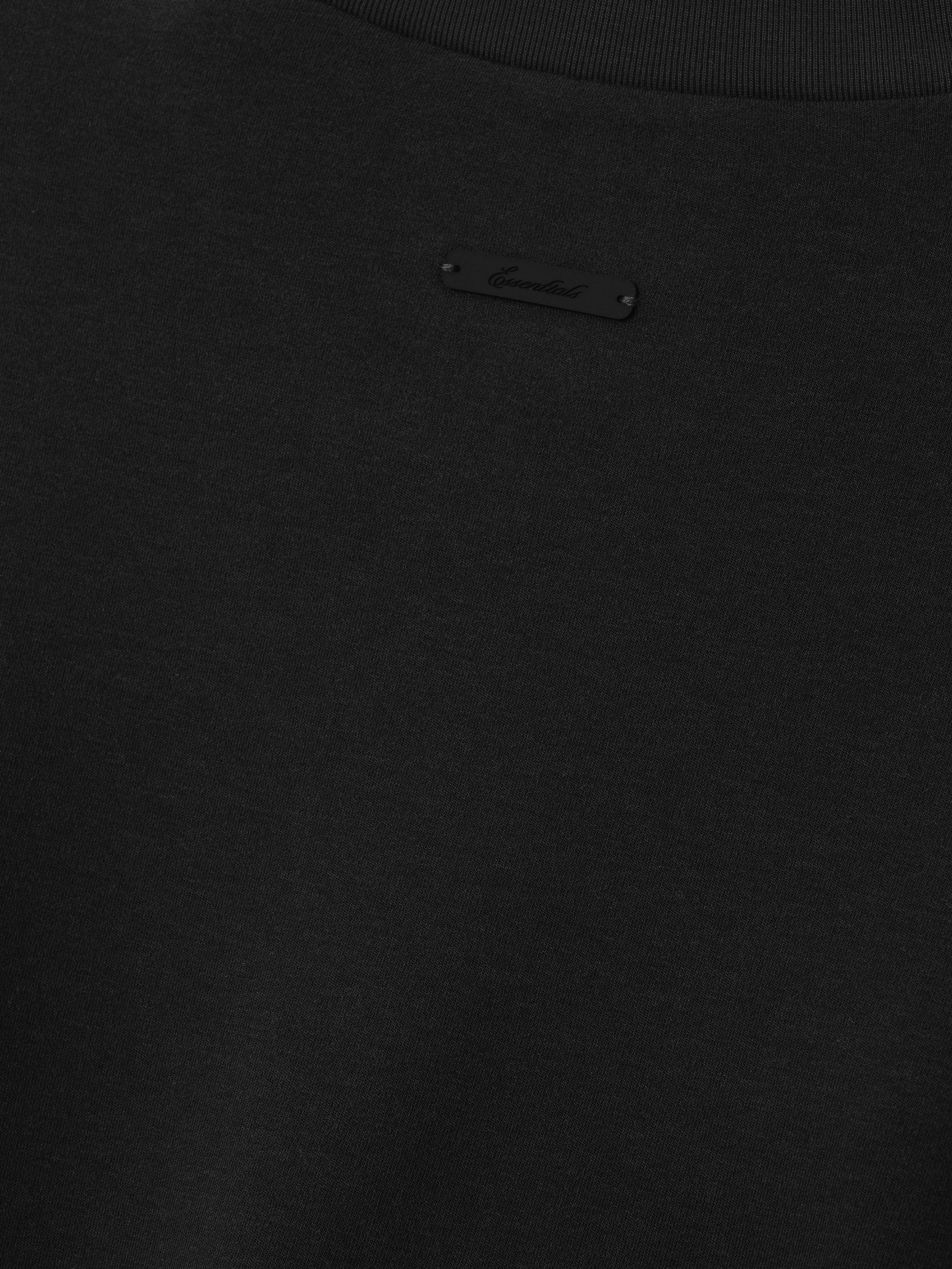 Close up of tee shirt with black essentials script label