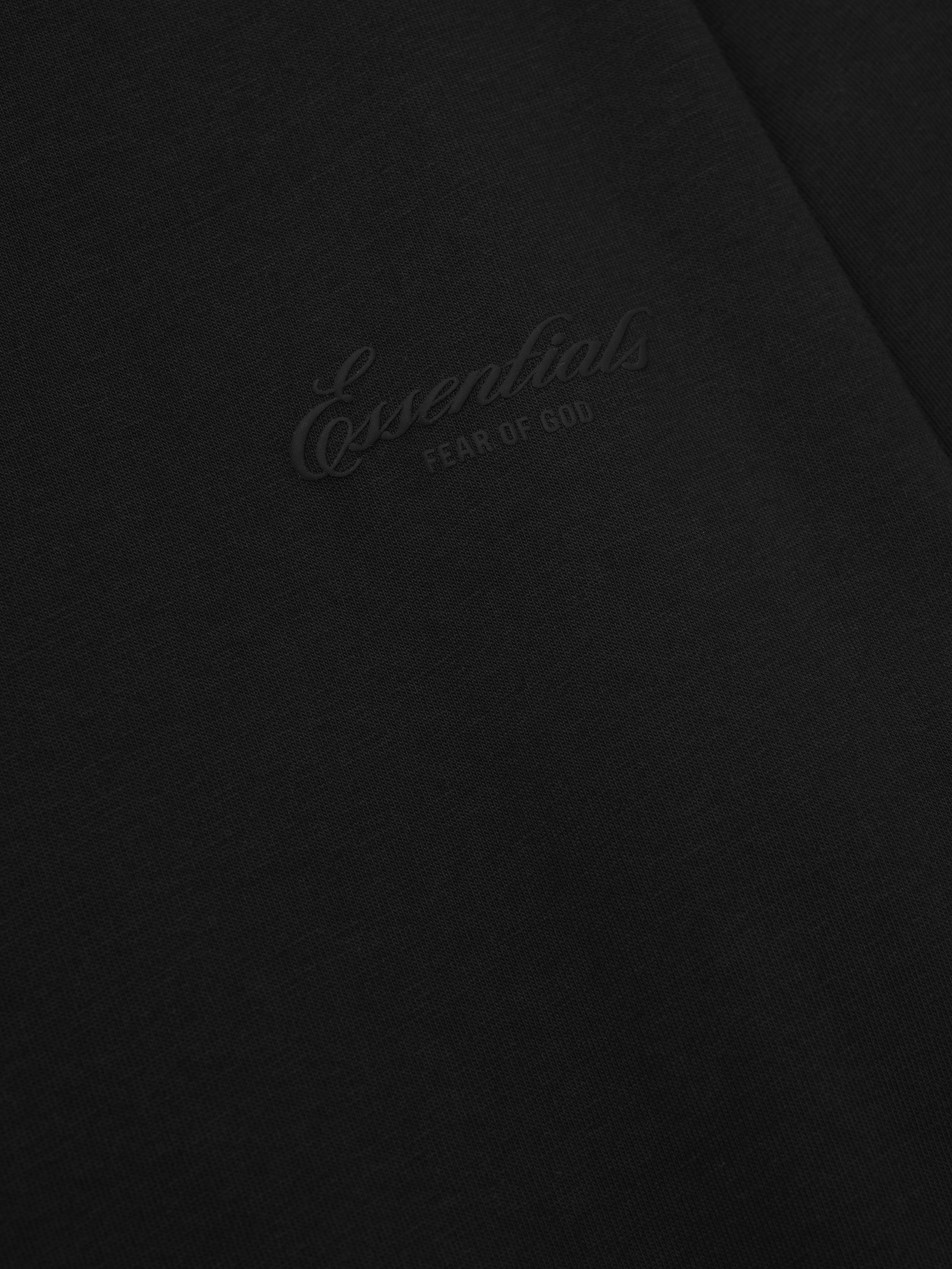 close-up of black cotton jersey fabric with subtle tonal puff-printed Essentials Fear of God logo on long sleeve tee
