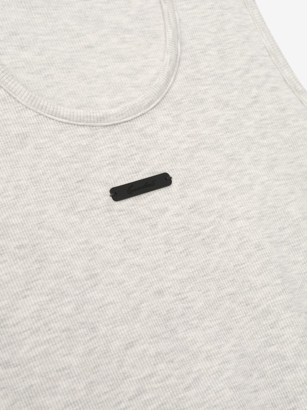 close-up of light cream ribbed cotton-rayon-spandex tank top with U-neck and small black logo patch on chest