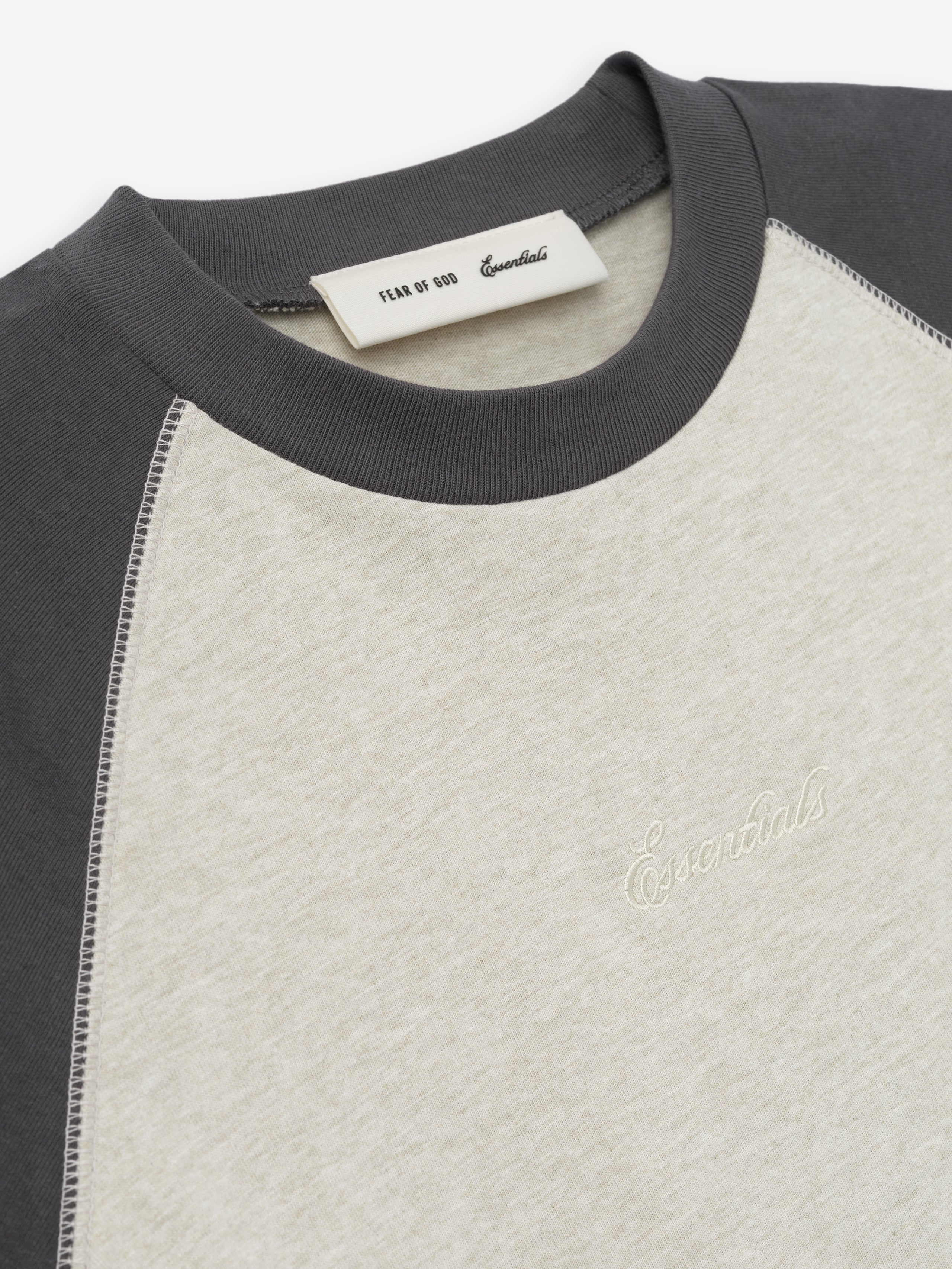 close-up of cream and charcoal raglan sleeve cotton baseball tee with rib-knit crewneck and embroidered Essentials logo