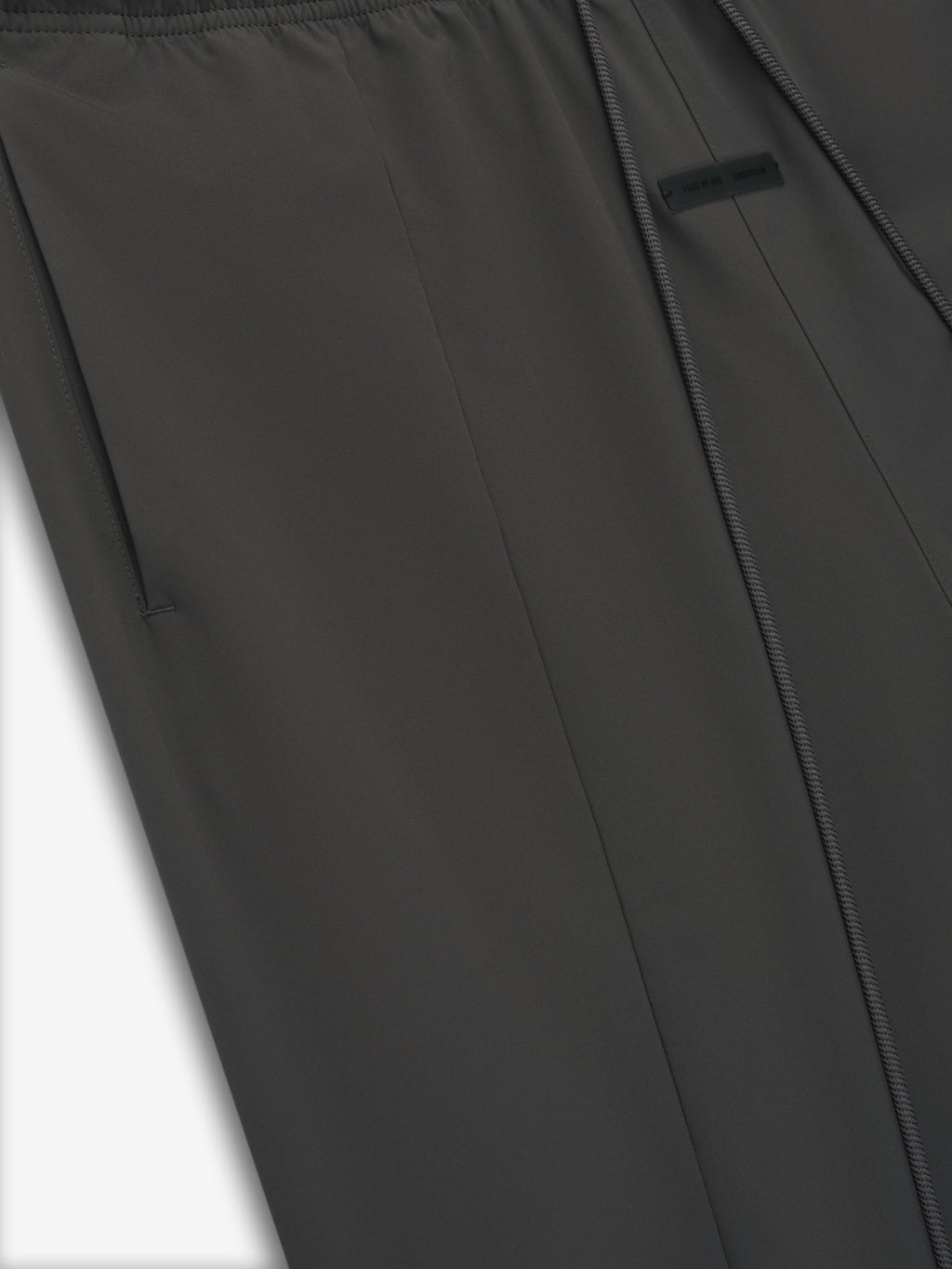 Close-up of iron grey Tech Nylon Relaxed Track Pant showing smooth fabric, side pocket, and subtle seam detail