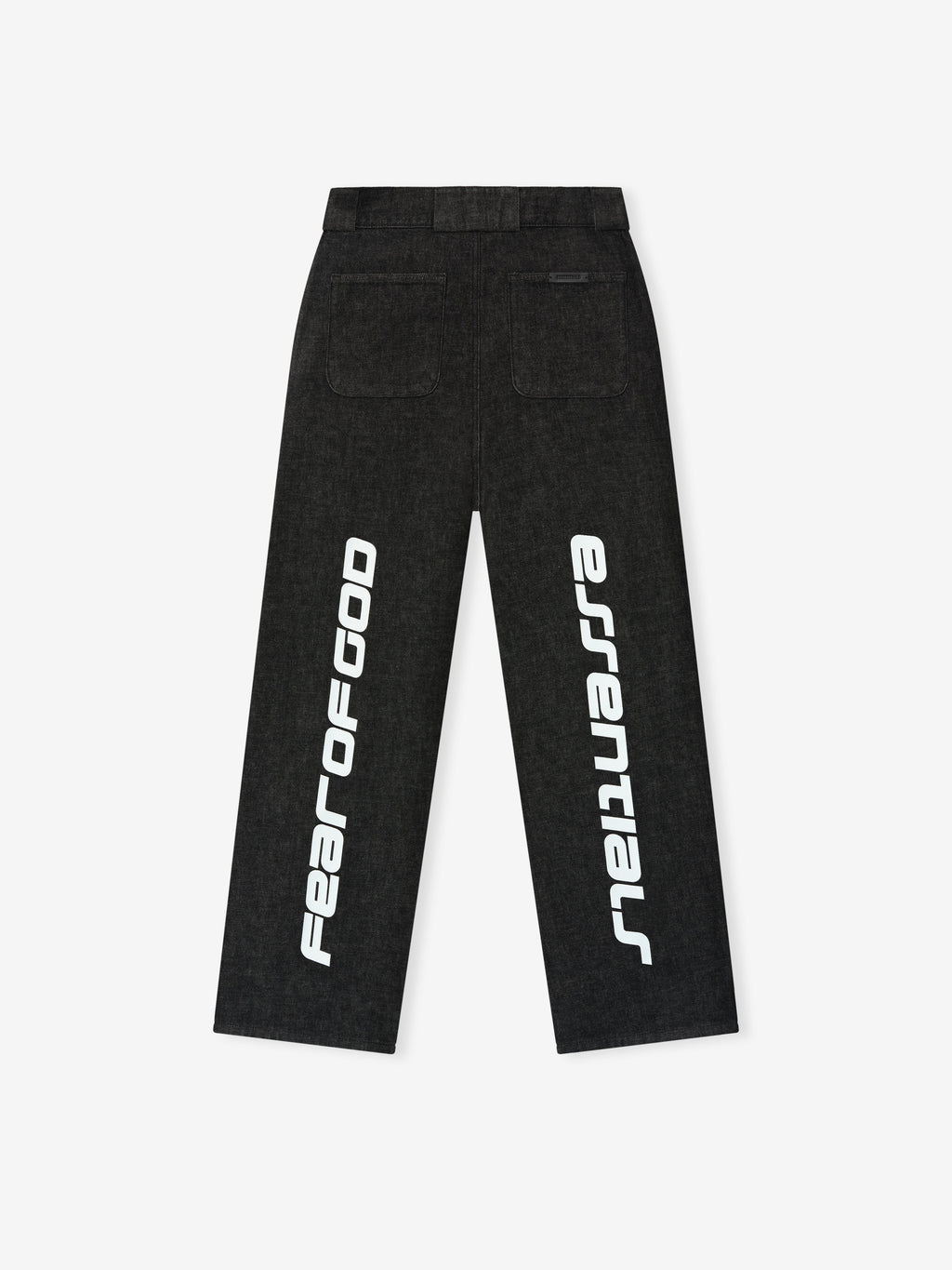 Back view of vintage black denim work pants featuring large white vertical Fear of God Essentials text on legs