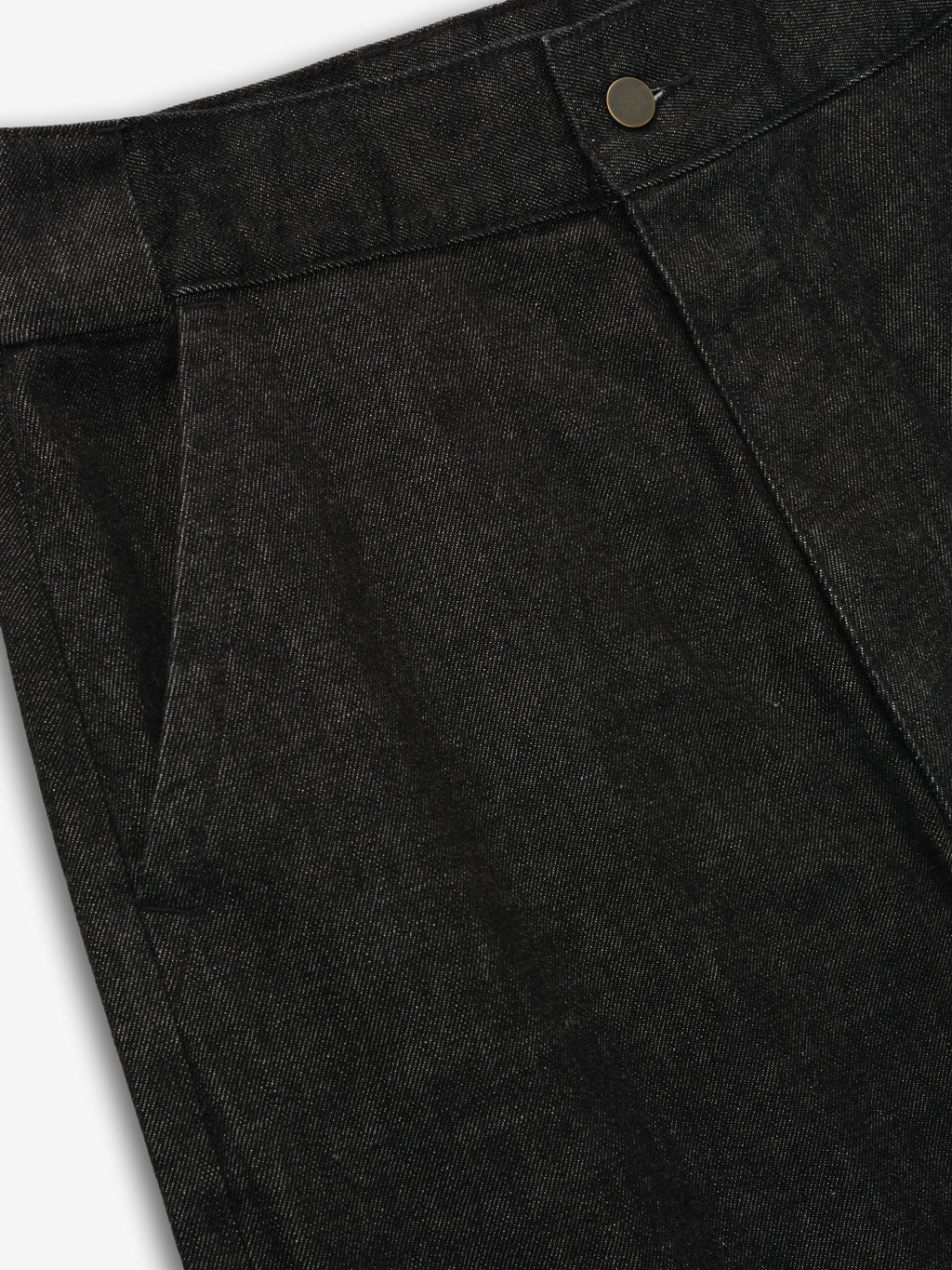Close-up of vintage black denim work pant waistband and front pocket with button detail on gray background