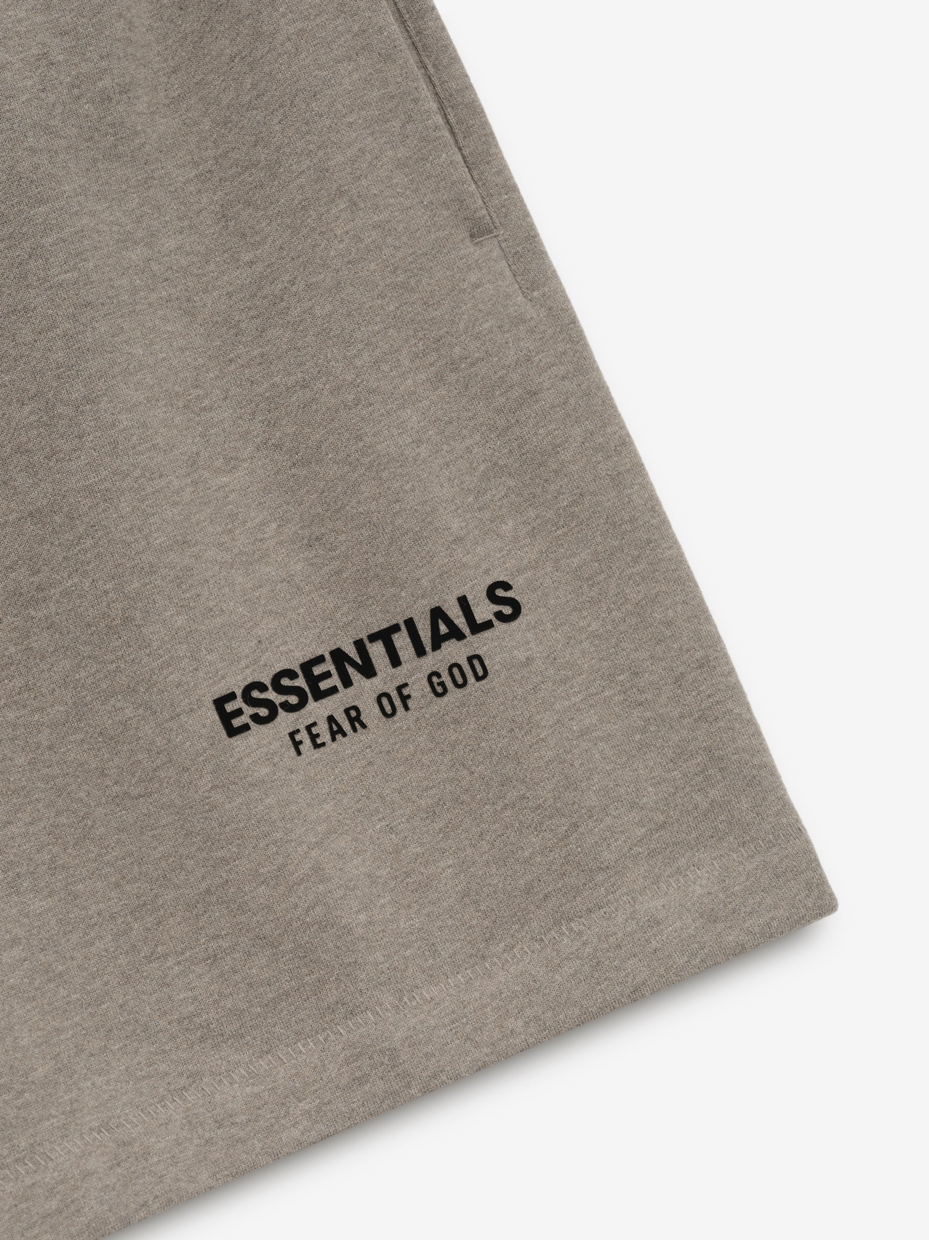 Close-up of Homestead Heather Classic Sweatshort featuring black Essentials Fear of God logo print near hem