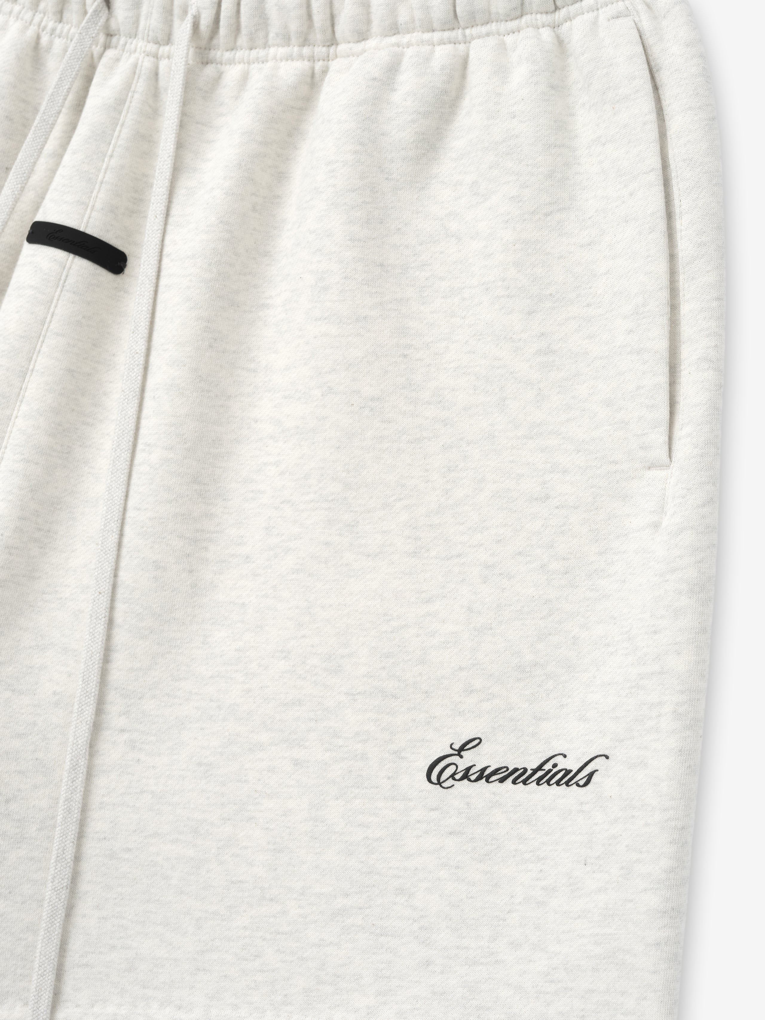 White sweatpants with 'essentials' embroidery on a white background