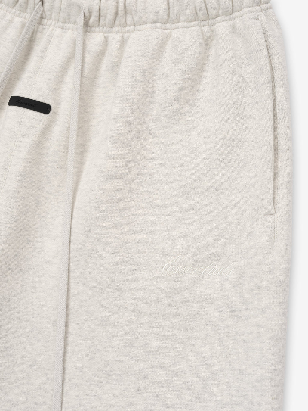 Close-up of light gray shorts with a black patch on a white background