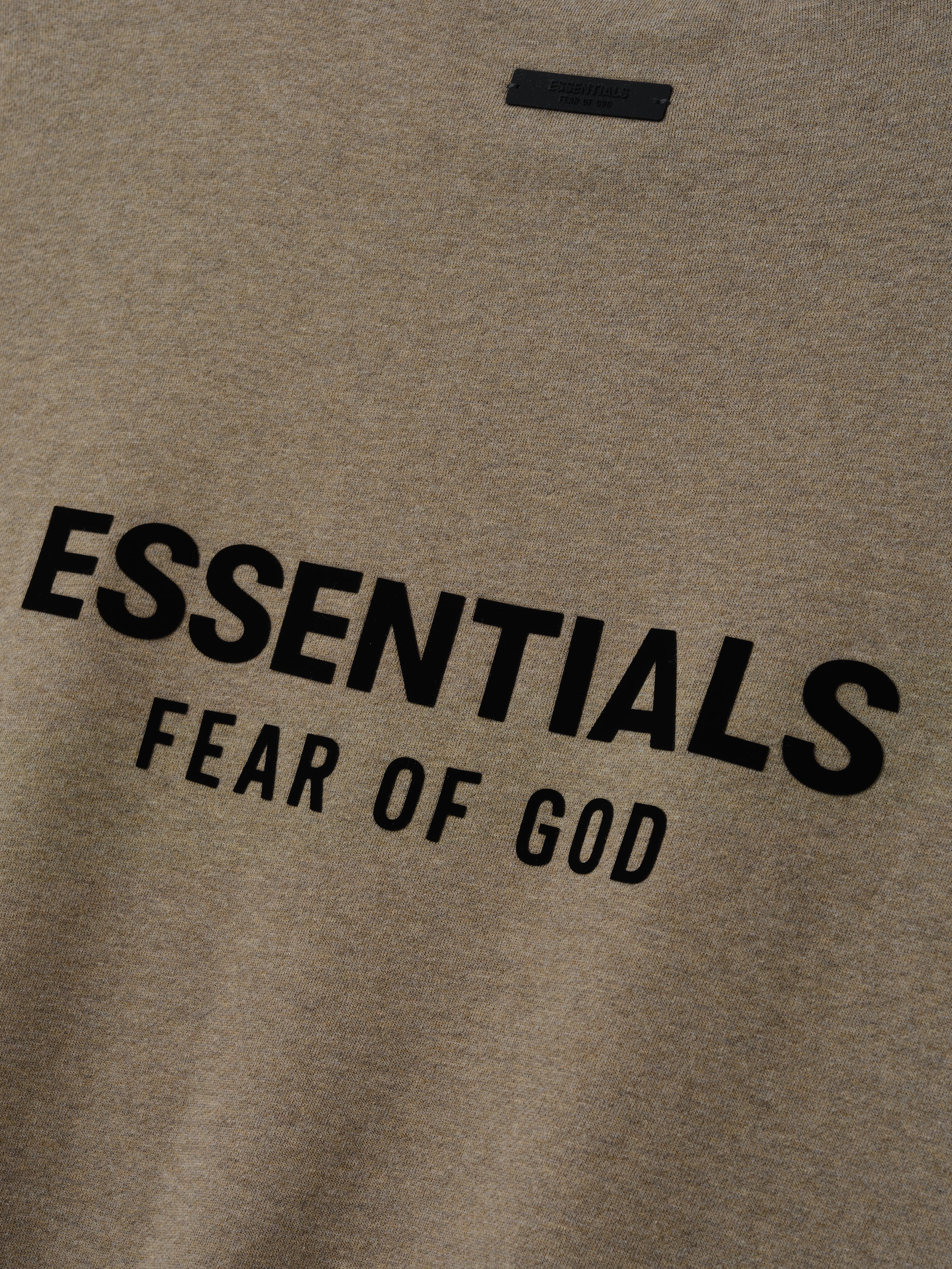 Close up of Homestead Heather sweatshirt with 'ESSENTIALS FEAR OF GOD' text logo