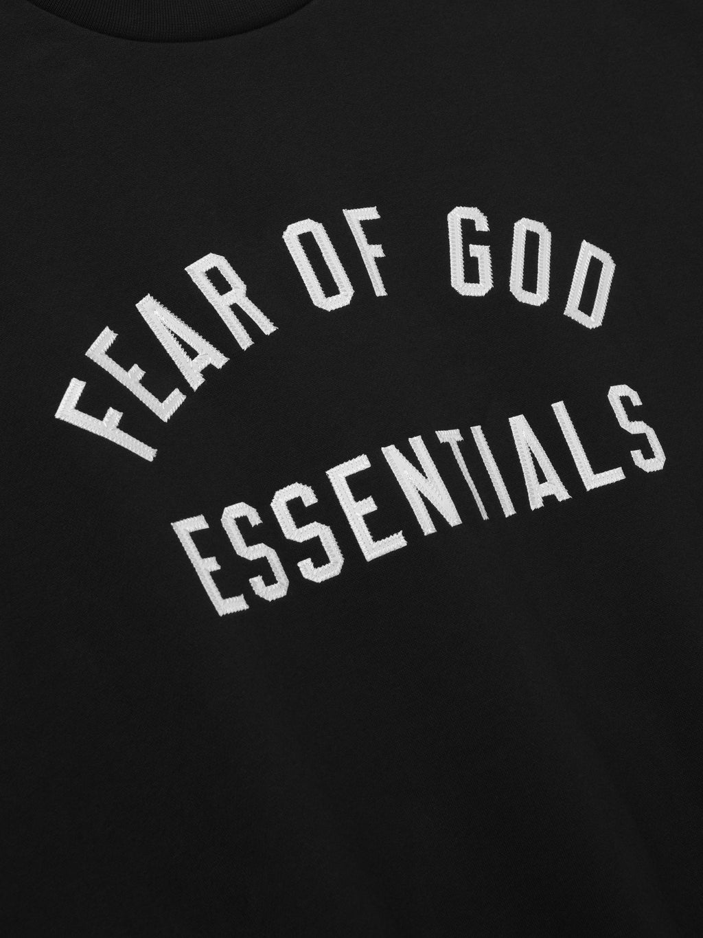 close-up of black fabric with white Fear of God Essentials arch logo embroidered on crewneck sweatshirt
